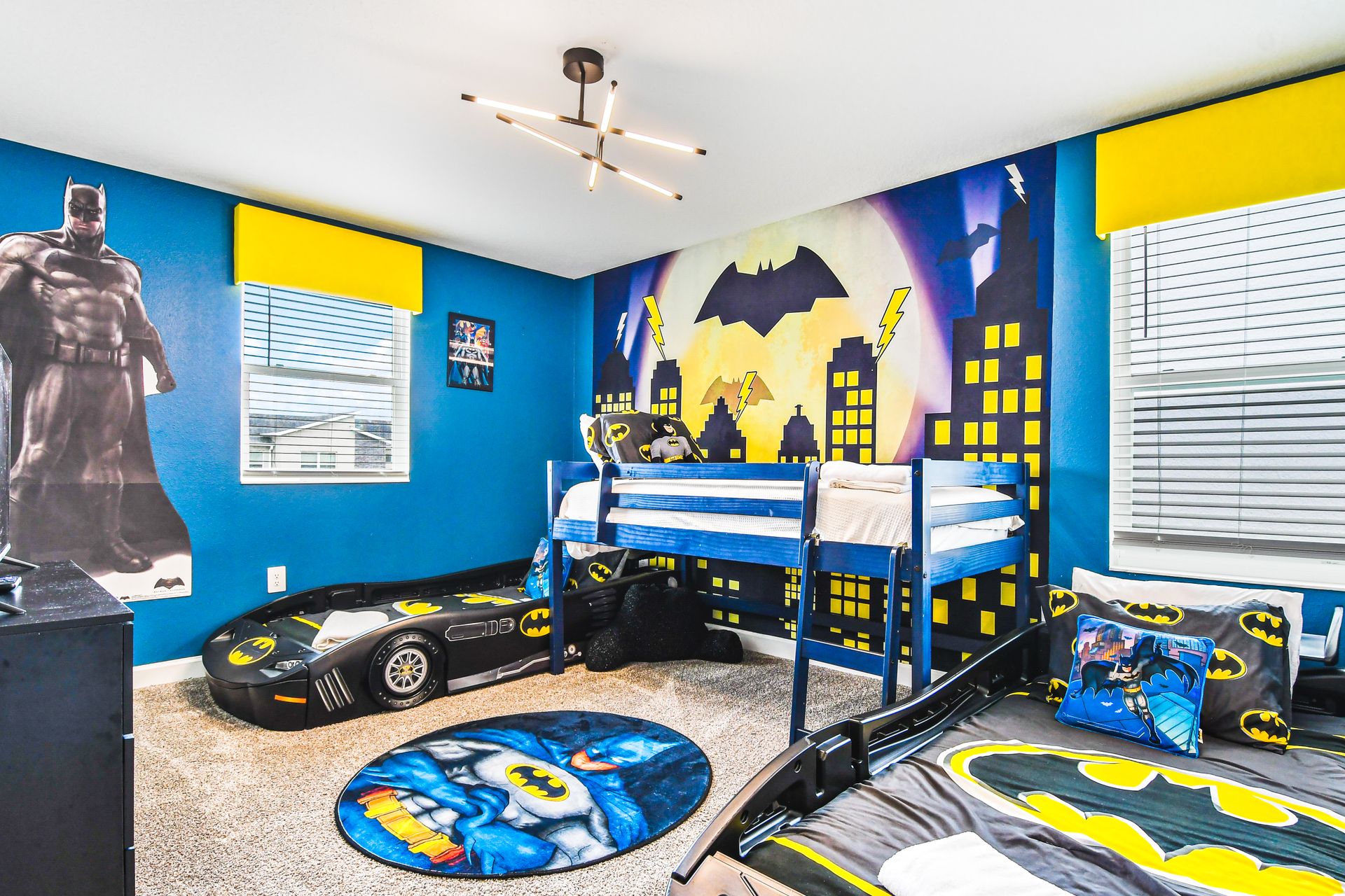 Dynamic Batman-themed kids' room with Gotham City murals, bat-signal decor, and car beds.