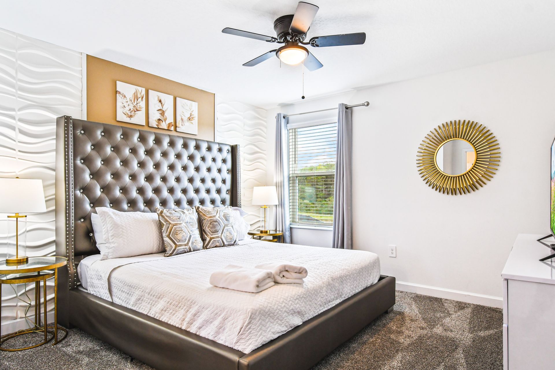 Luxurious bedroom featuring a tufted gray leather headboard with stud detailing against a textured 3D white wave accent wall.