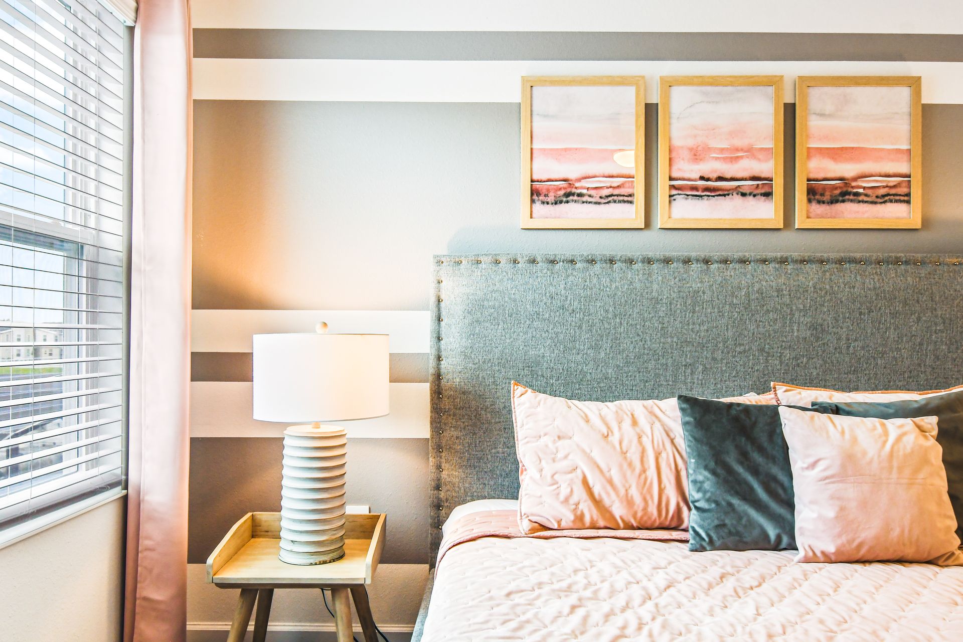 Close-up of a cozy bedroom with a soft gray upholstered headboard.