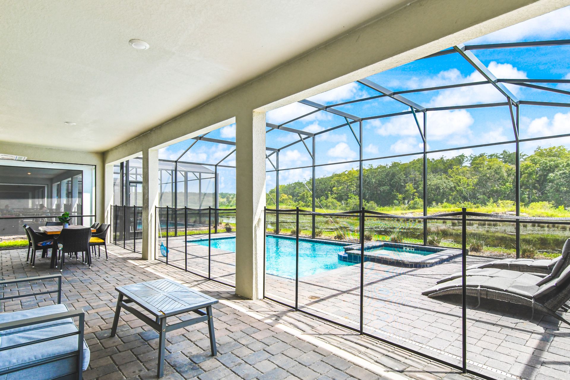Spacious screened patio with cozy seating, dining table, and poolside lounge chairs.