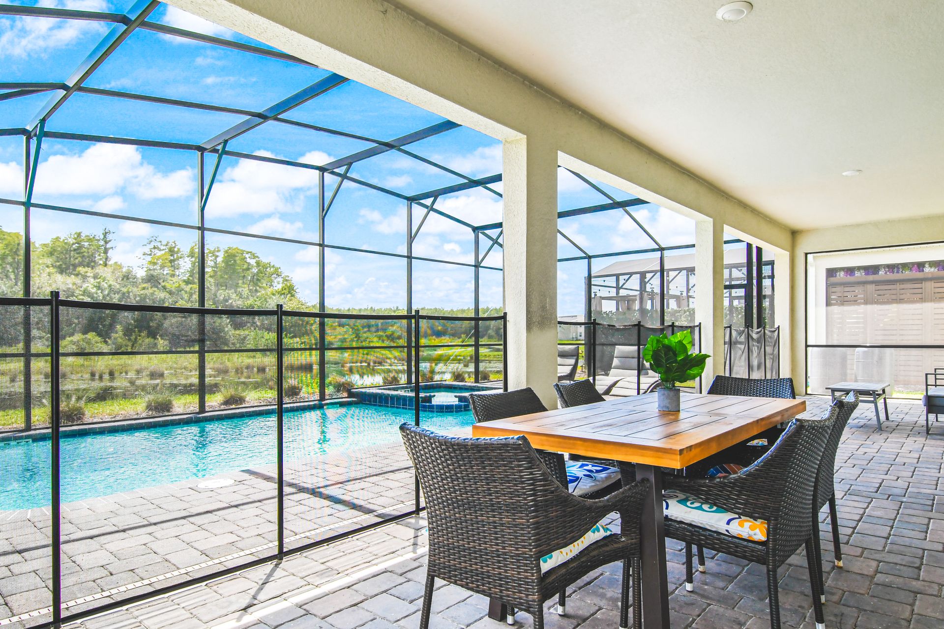 Covered patio with dining area overlooking a screened-in pool and peaceful lake views.