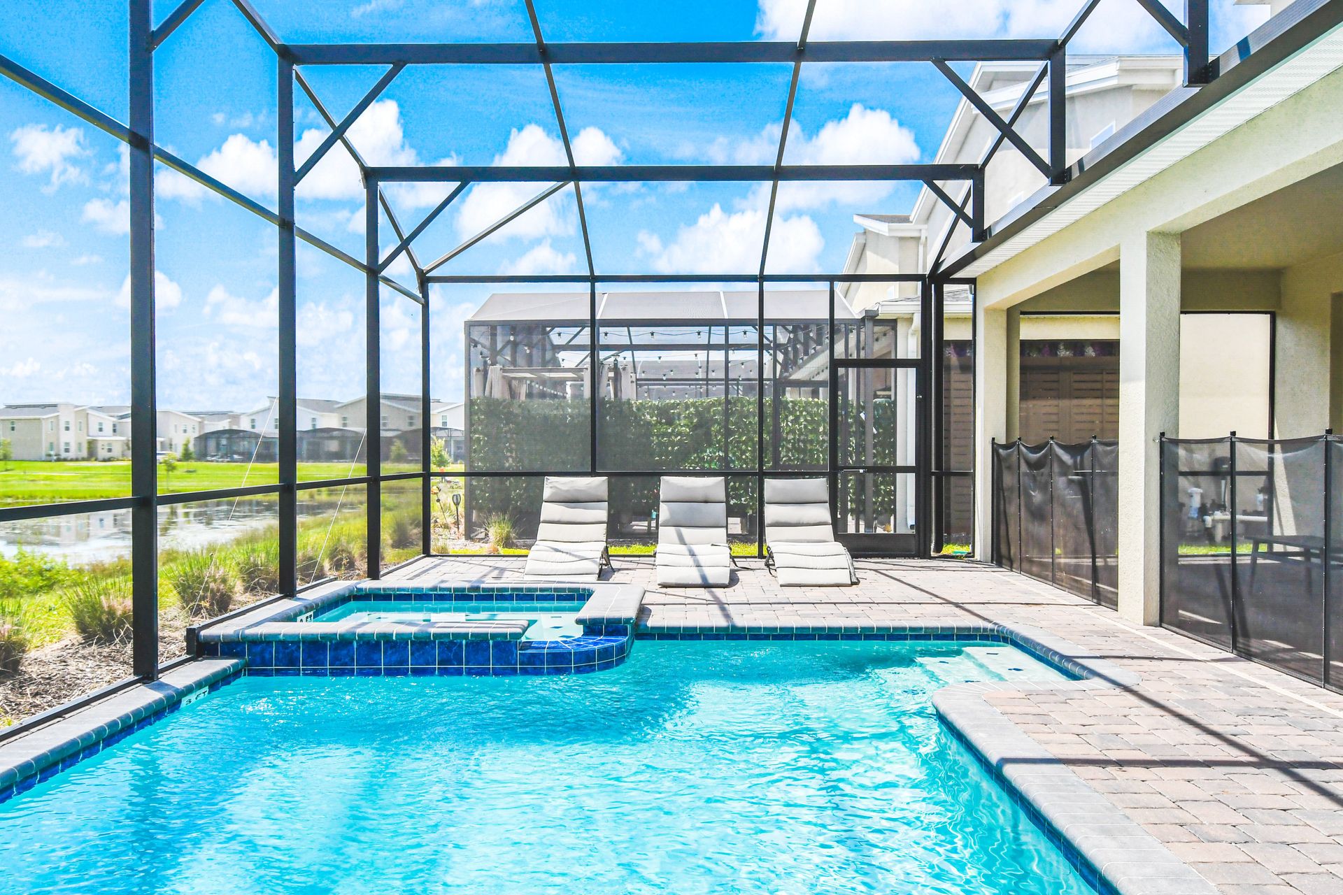 Inviting pool area with a screened enclosure, spa, and relaxing lounge chairs.