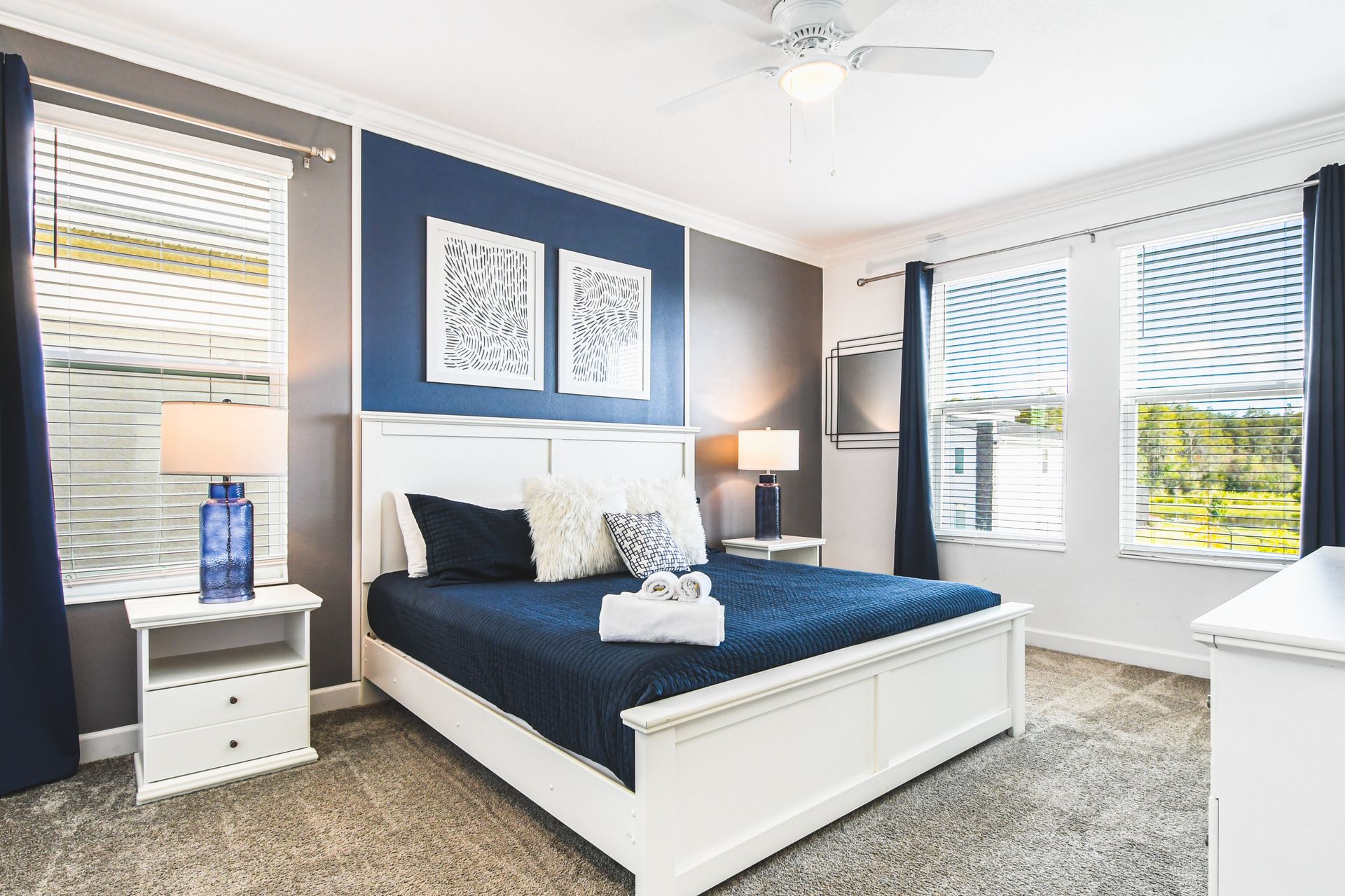 Bright and serene bedroom with king bed, TV, and stylish navy and white decor