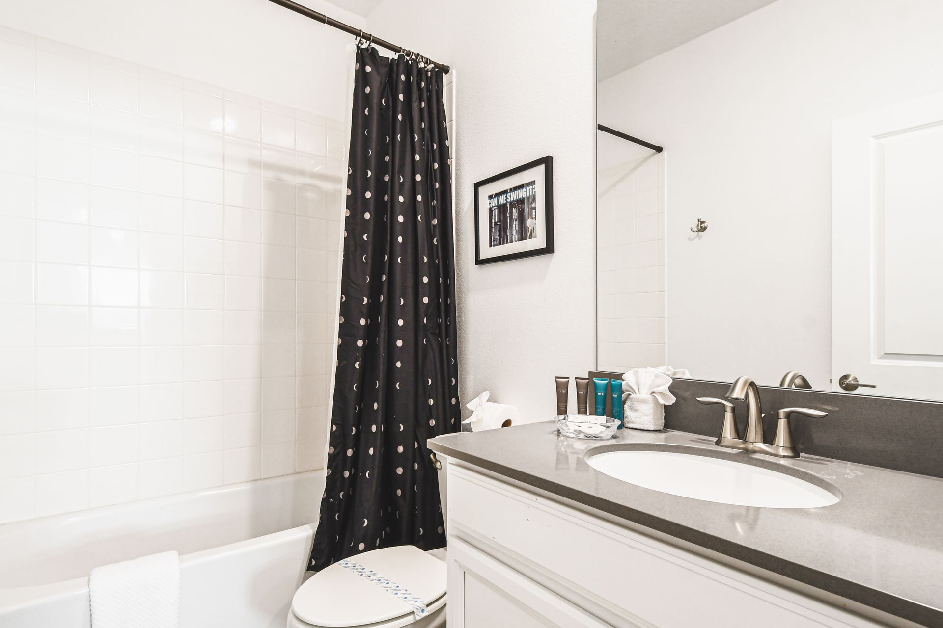 Stylish full bathroom with dark vanity, fun shower curtain, and bright tile tub combo