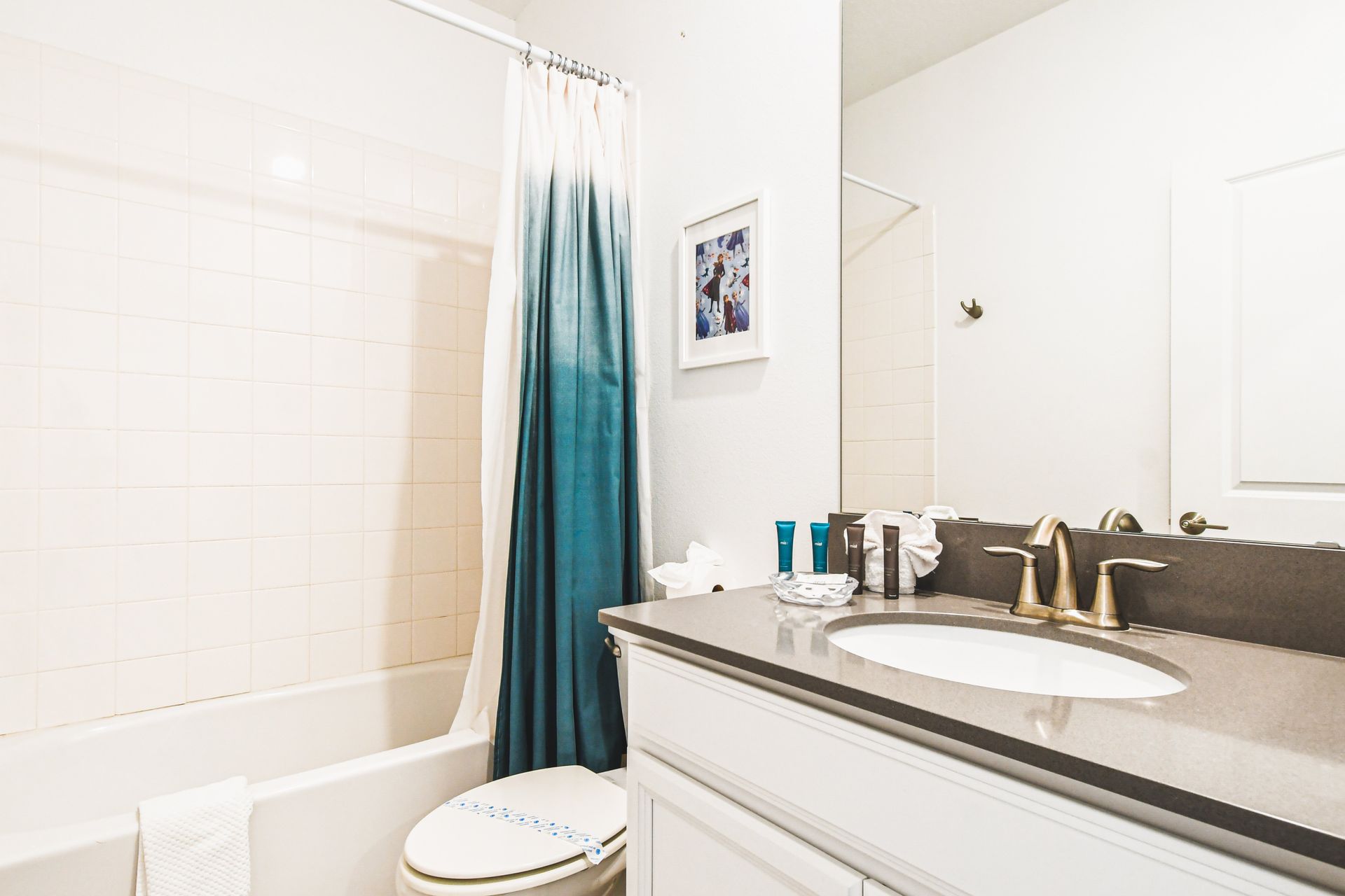 Stylish full bathroom with dark vanity, fun shower curtain, and bright tile tub combo