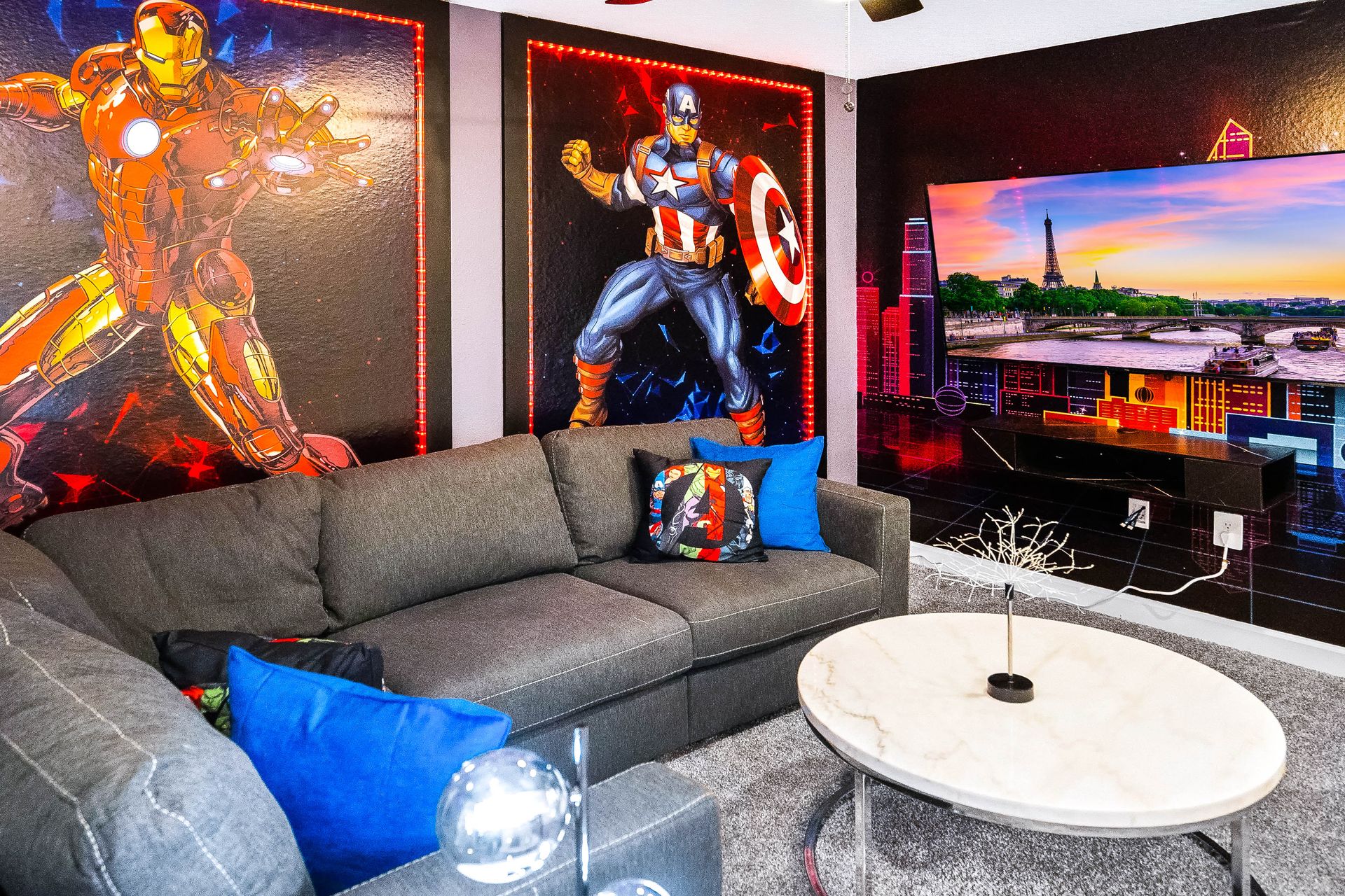 Superhero-themed room with vibrant murals, cozy sectional, and cinematic TV setup.