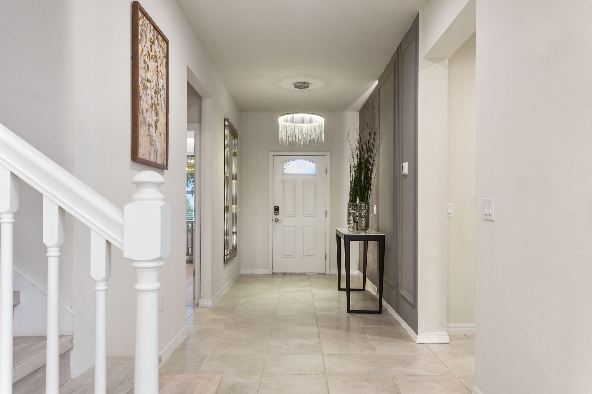 Elegant entryway with modern chandelier, neutral tones, and stylish decor touches