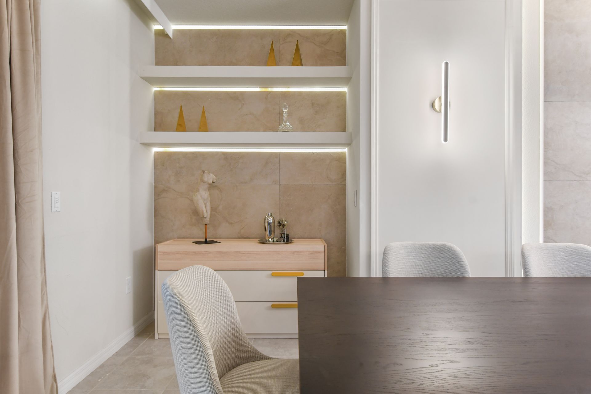 Sophisticated corner nook with built-in shelves, accent lighting, and décor.