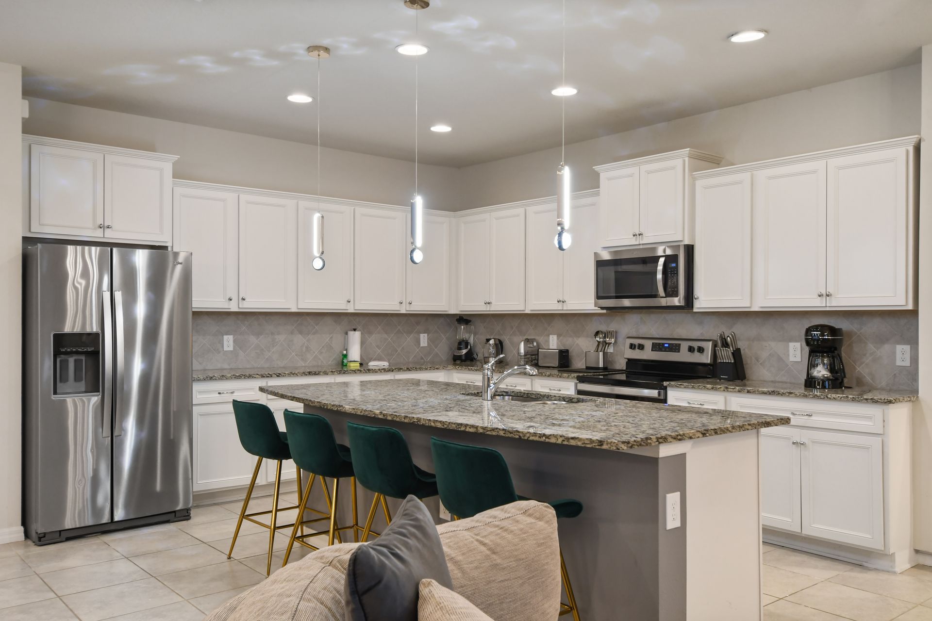 Modern chef’s kitchen with granite counters, sleek appliances & stylish lighting!