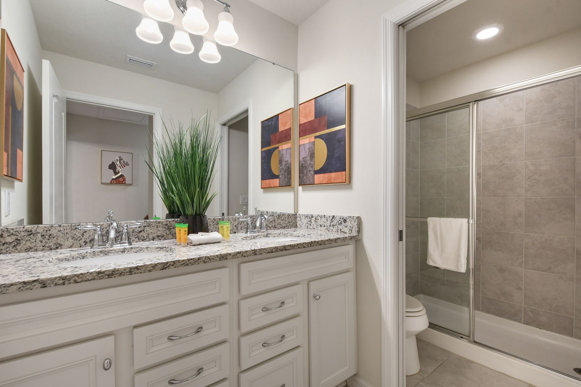 Modern bathroom with dual sinks, granite countertops & a sleek glass walk-in shower!