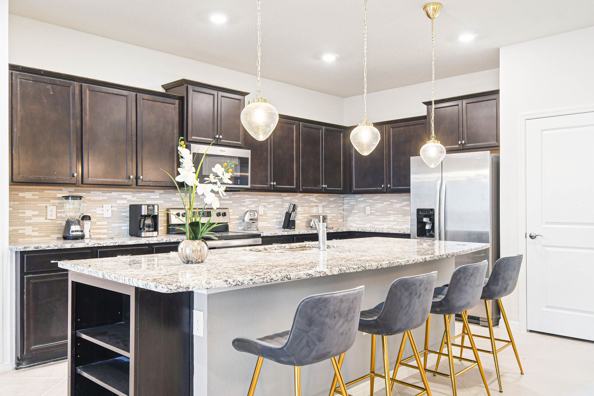 Stylish chef’s kitchen with granite island, modern lighting, and sleek finishes
