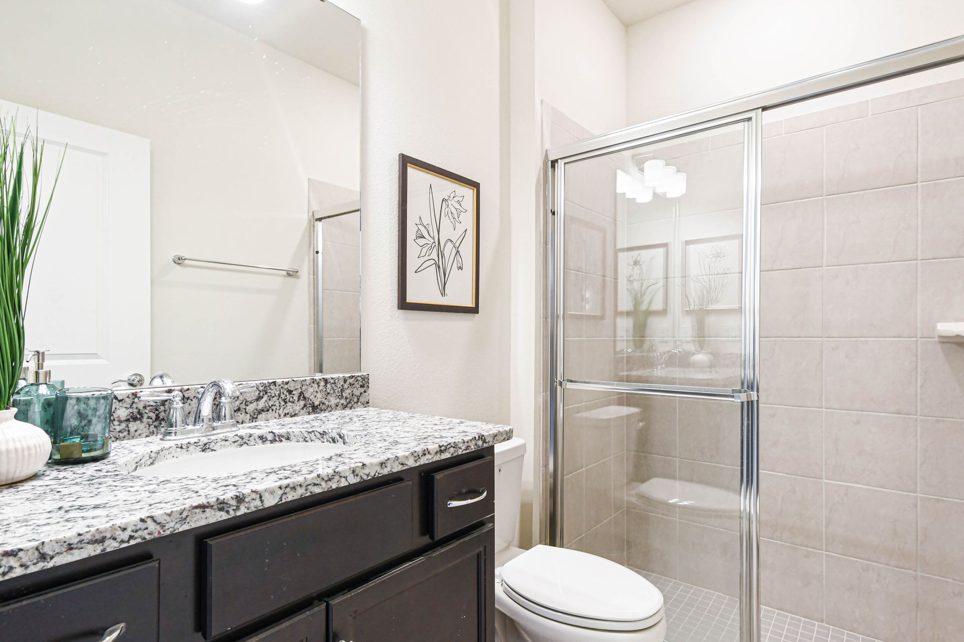 Modern full bath with granite vanity, glass walk-in shower, and sleek neutral tones