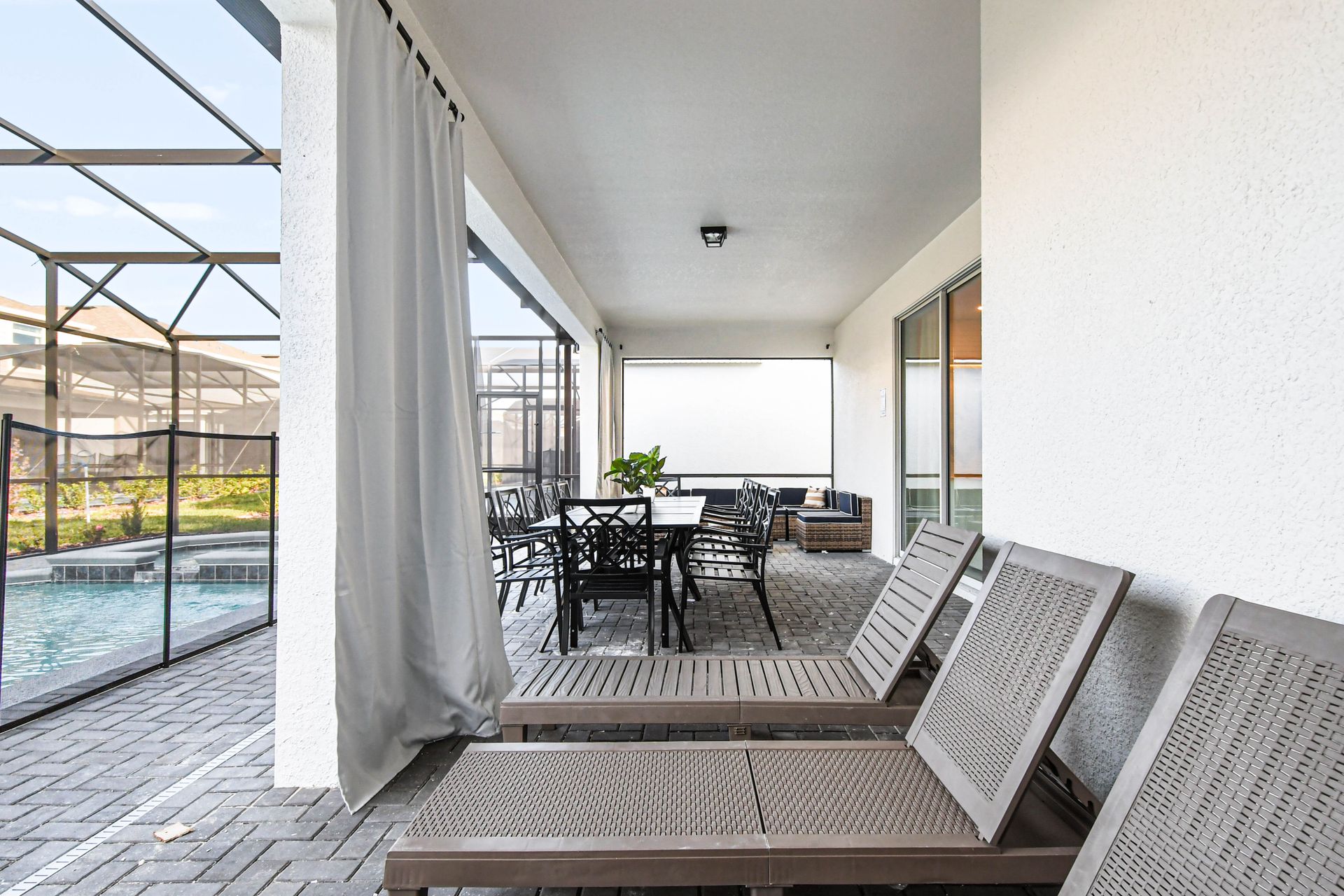 Relaxing poolside patio with loungers, dining space, and covered outdoor seating