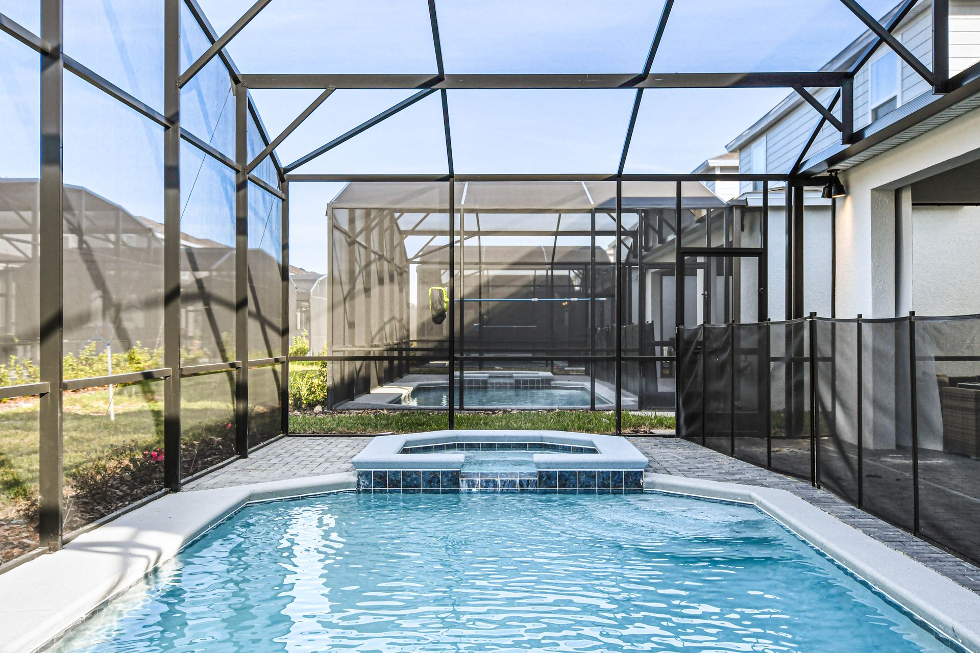 Private screened-in pool and spa with safety fence, patio seating, and sunny vibes