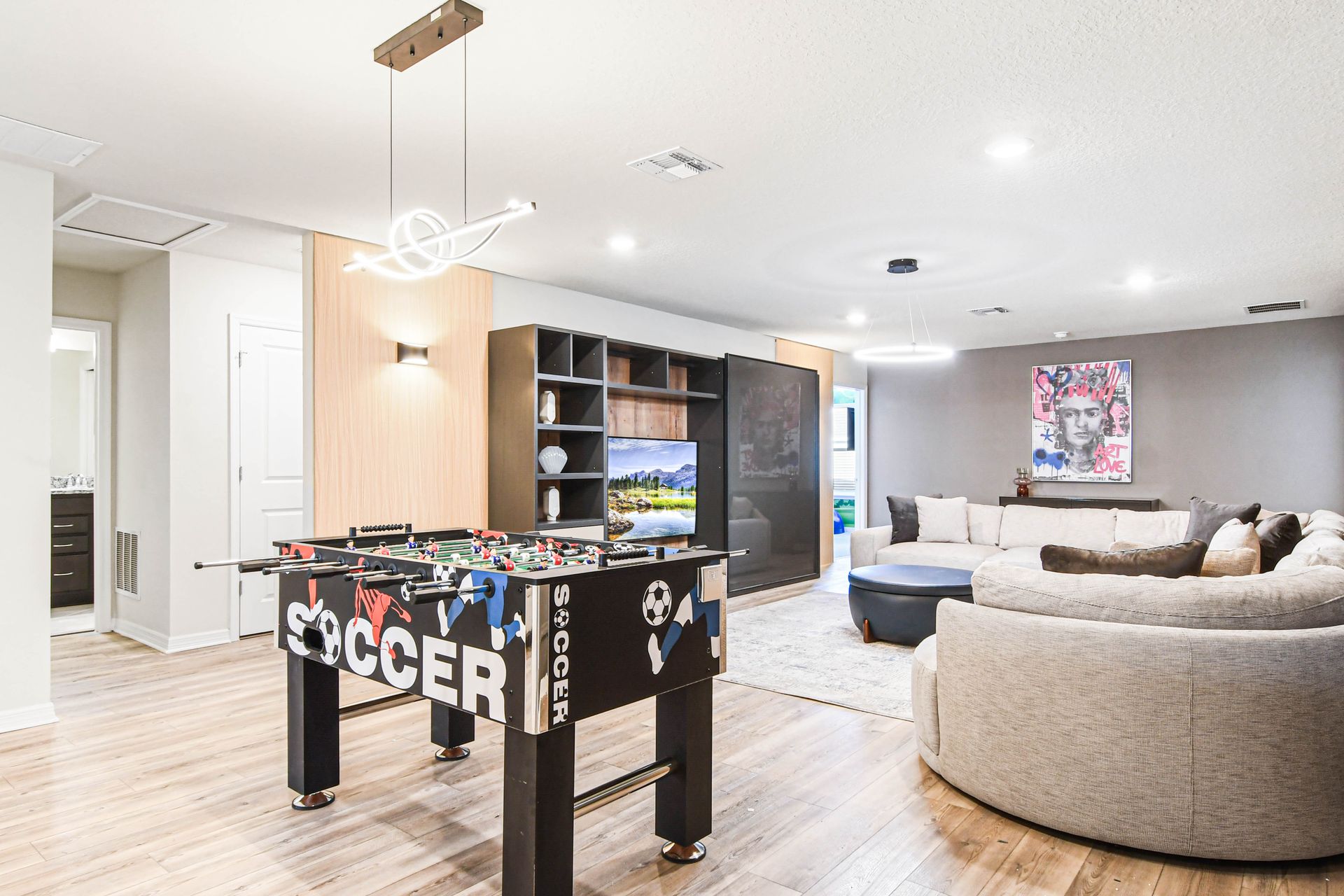 Stylish game loft with foosball, curved sectional, and modern lighting design