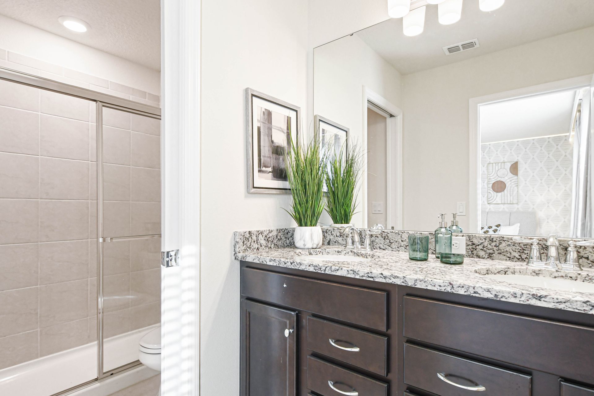 Sleek bathroom with granite countertop, walk-in shower, and modern decor touches