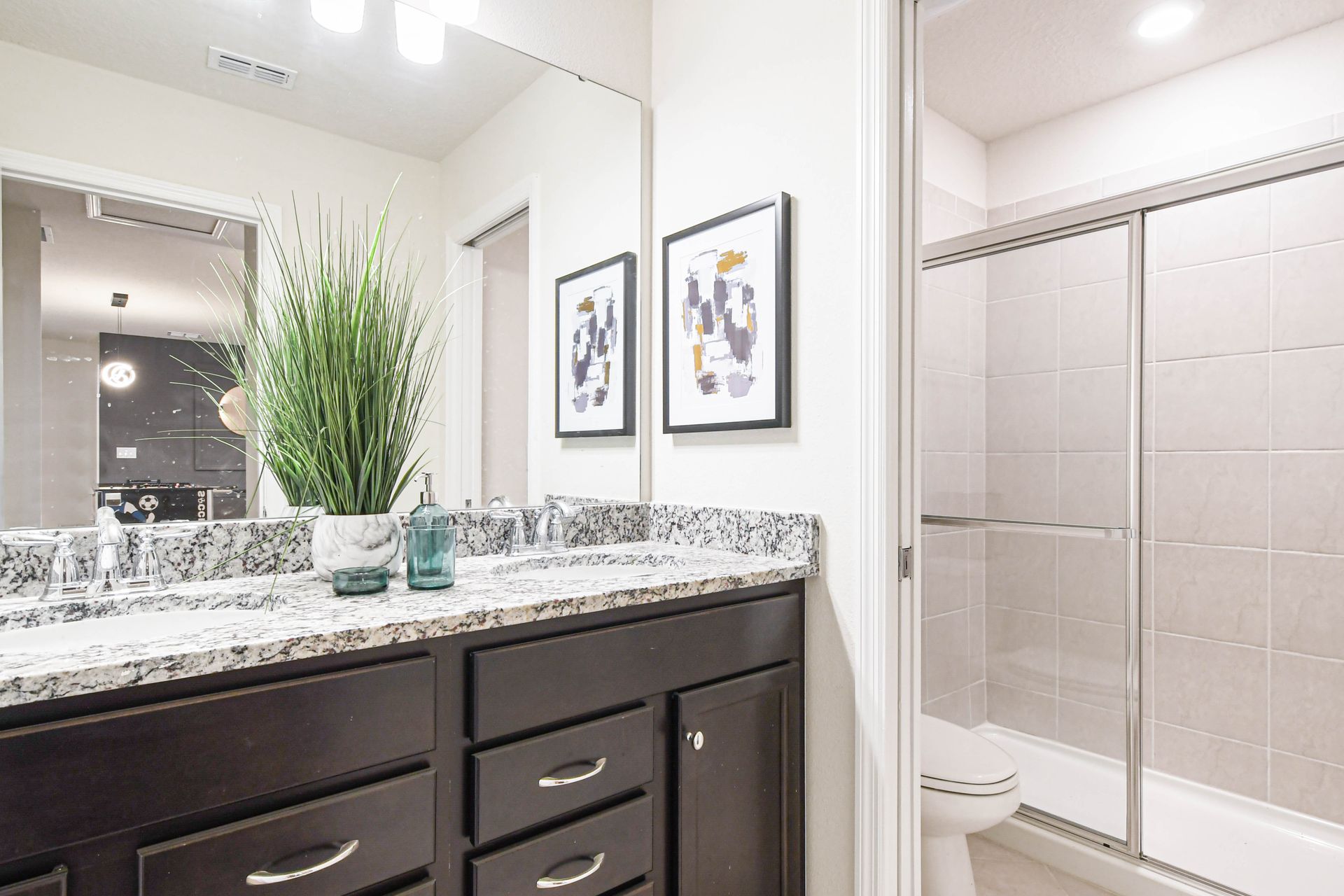 Contemporary bathroom with granite counters, glass shower, and game room access view