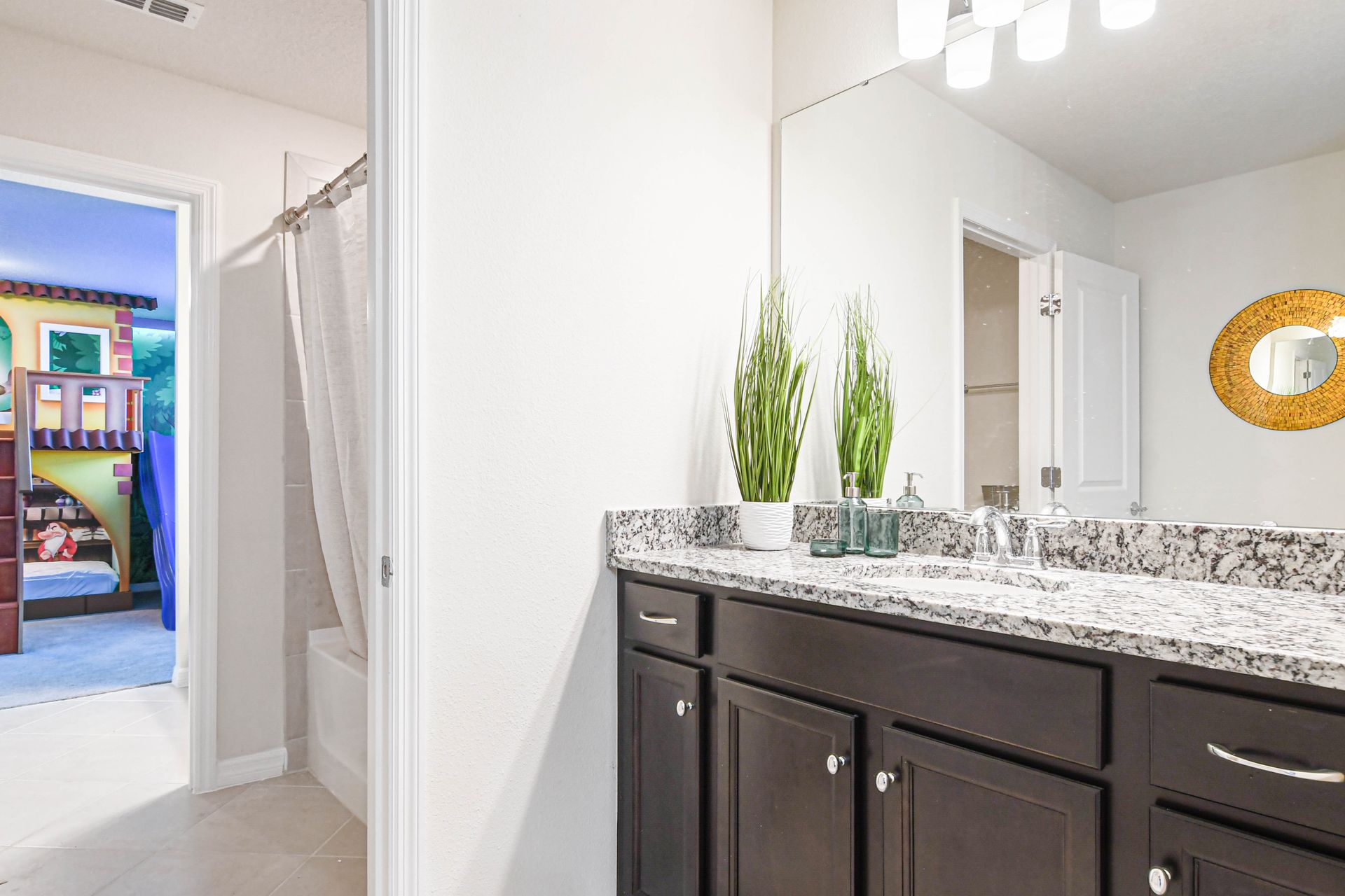 Charming bathroom with granite vanity, tub-shower combo, and access to themed kids' room