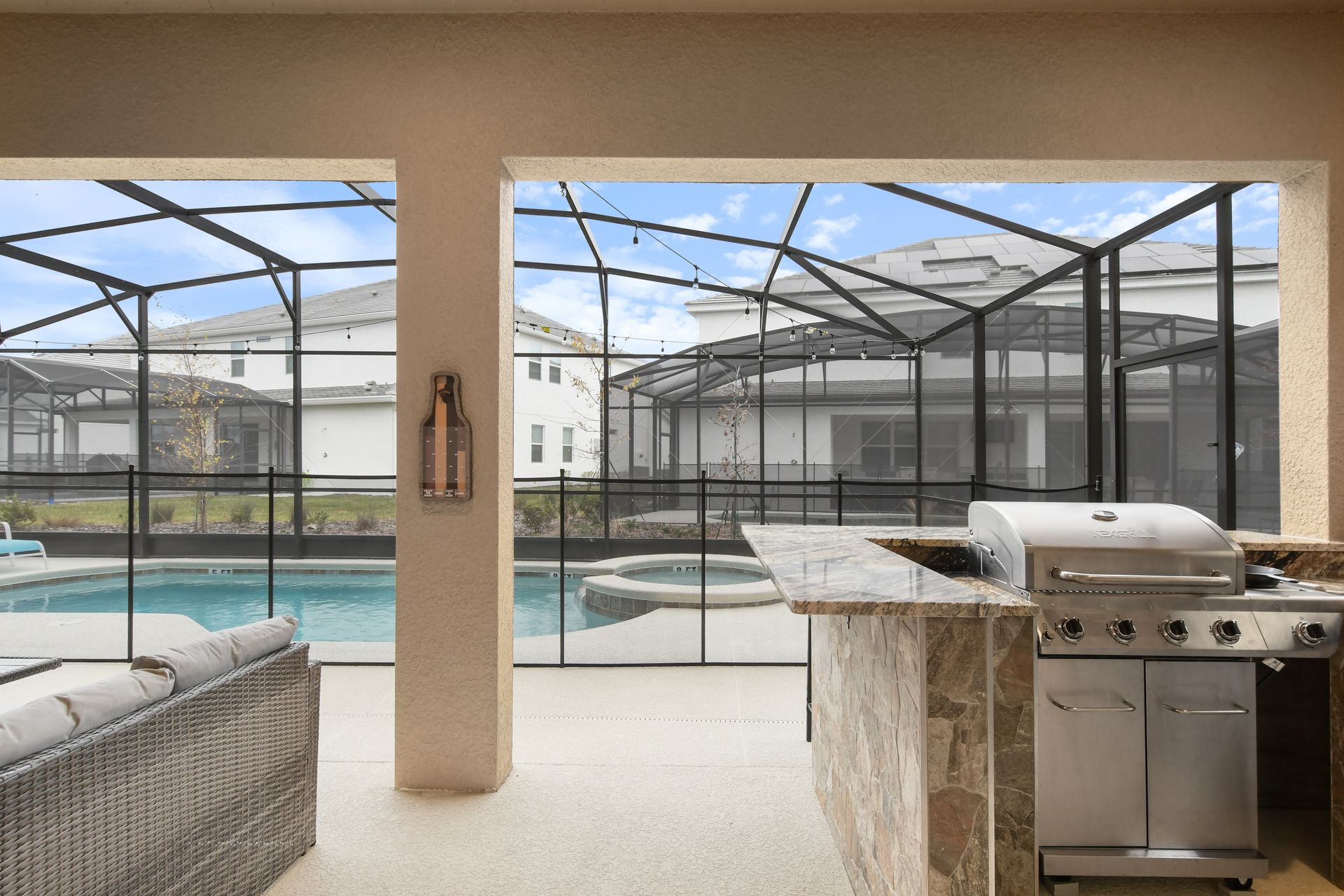 A beautiful outdoor kitchen and grilling area with a view of the screened-in pool and spa. 