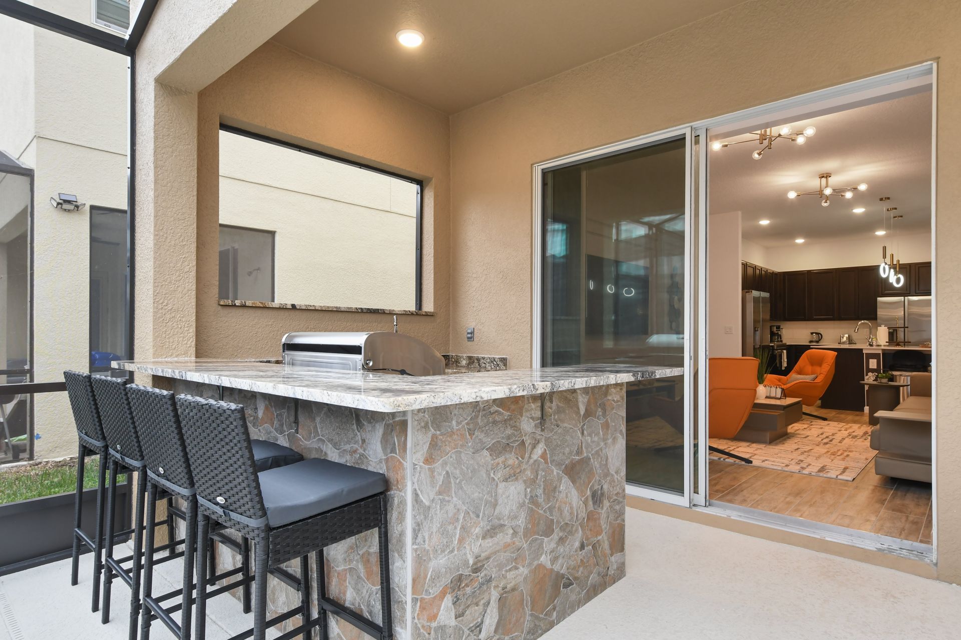 Stylish outdoor bar with stone accents, high-top seating, and a built-in grill station.