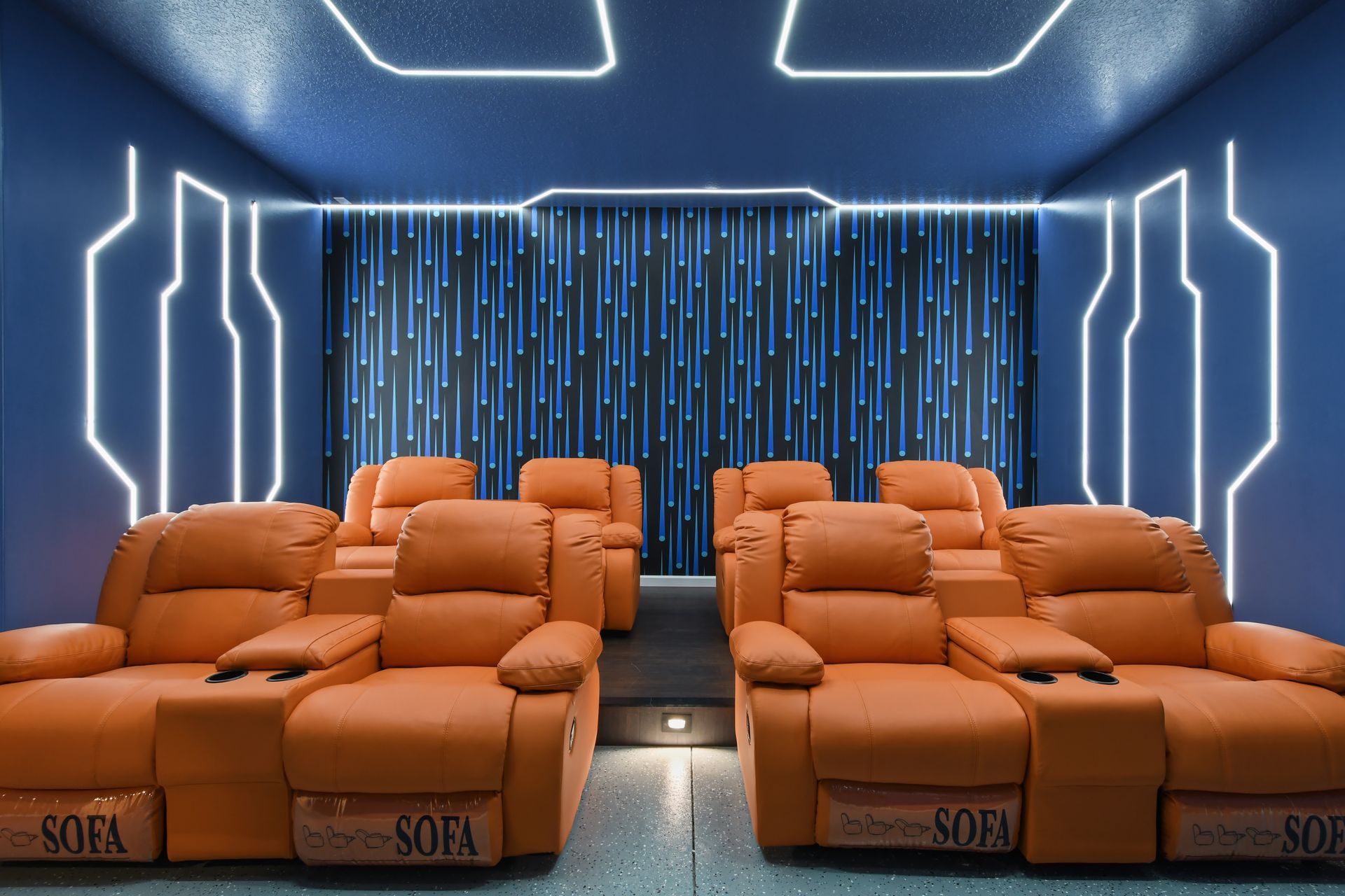 Futuristic home theater with plush recliners, neon lighting, and an immersive ambiance.