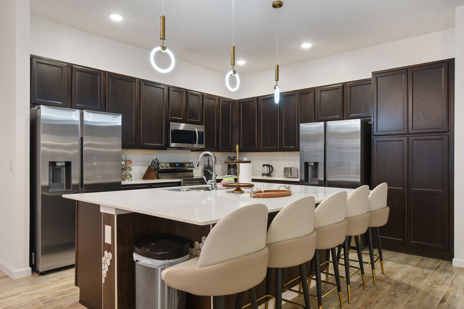 Modern gourmet kitchen with sleek dark cabinets, stainless steel appliances, and island seating.