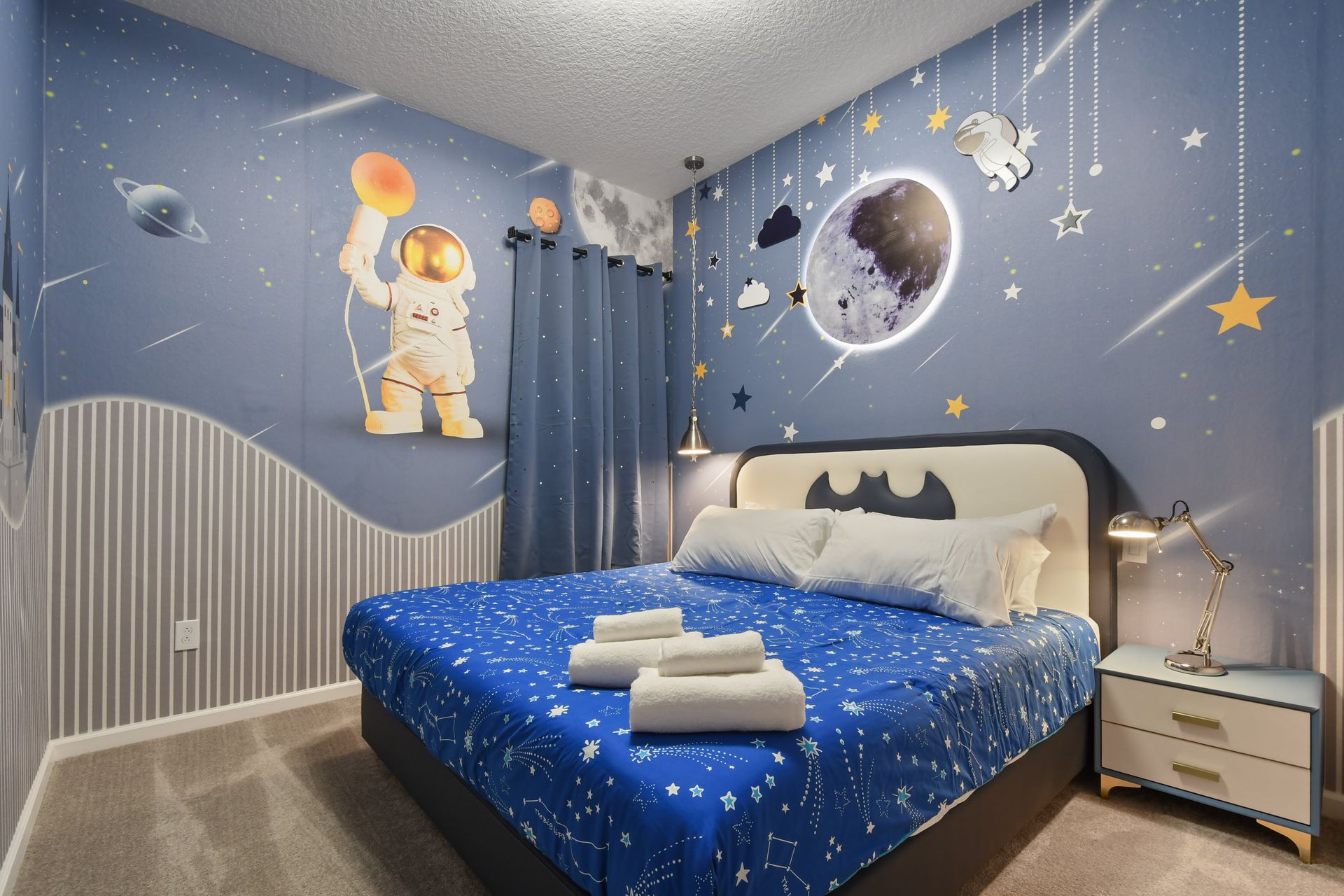 Space-themed bedroom with glowing moon decor, astronaut murals, and a cozy starry bed.