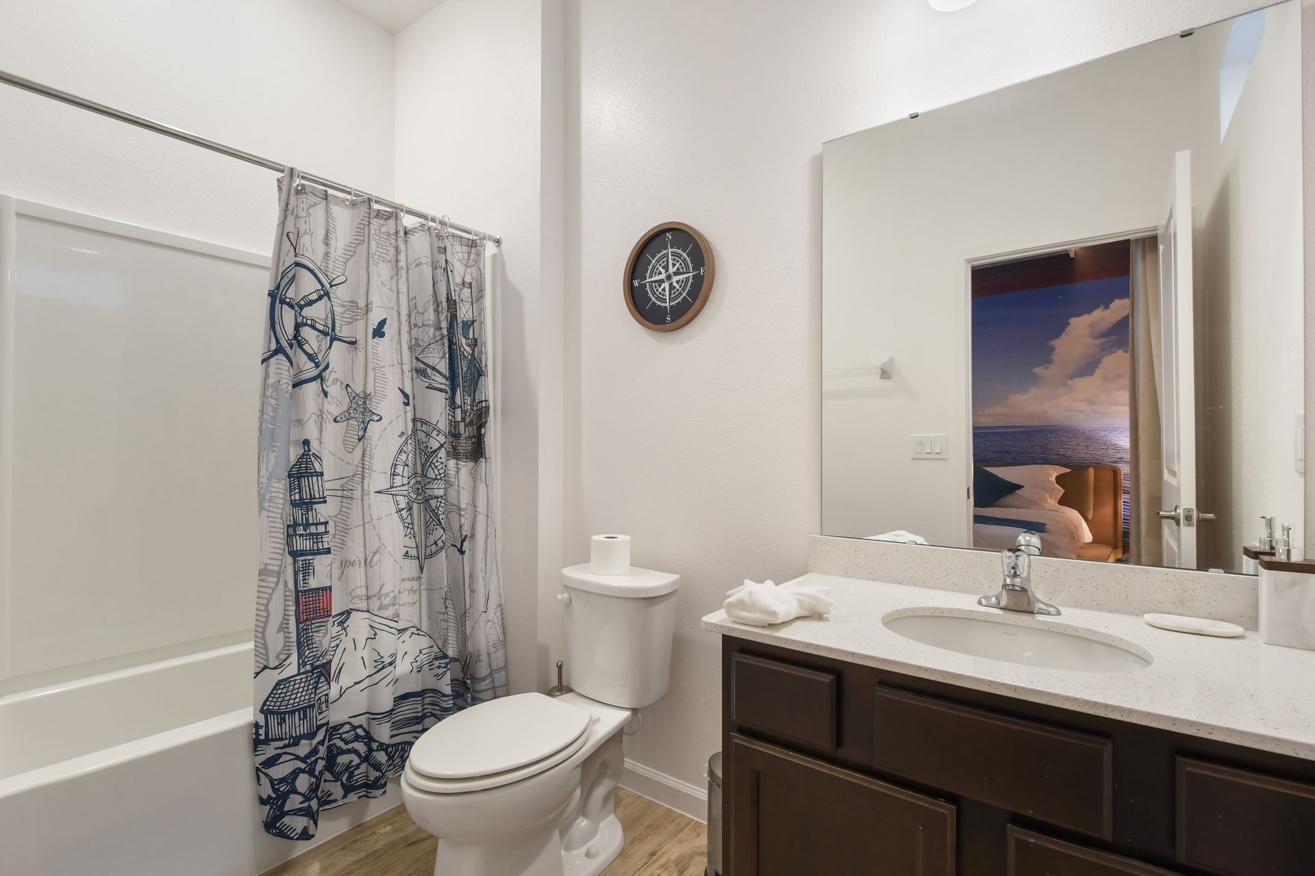 Nautical-themed bathroom with modern vanity, bright lighting, and a relaxing tub!