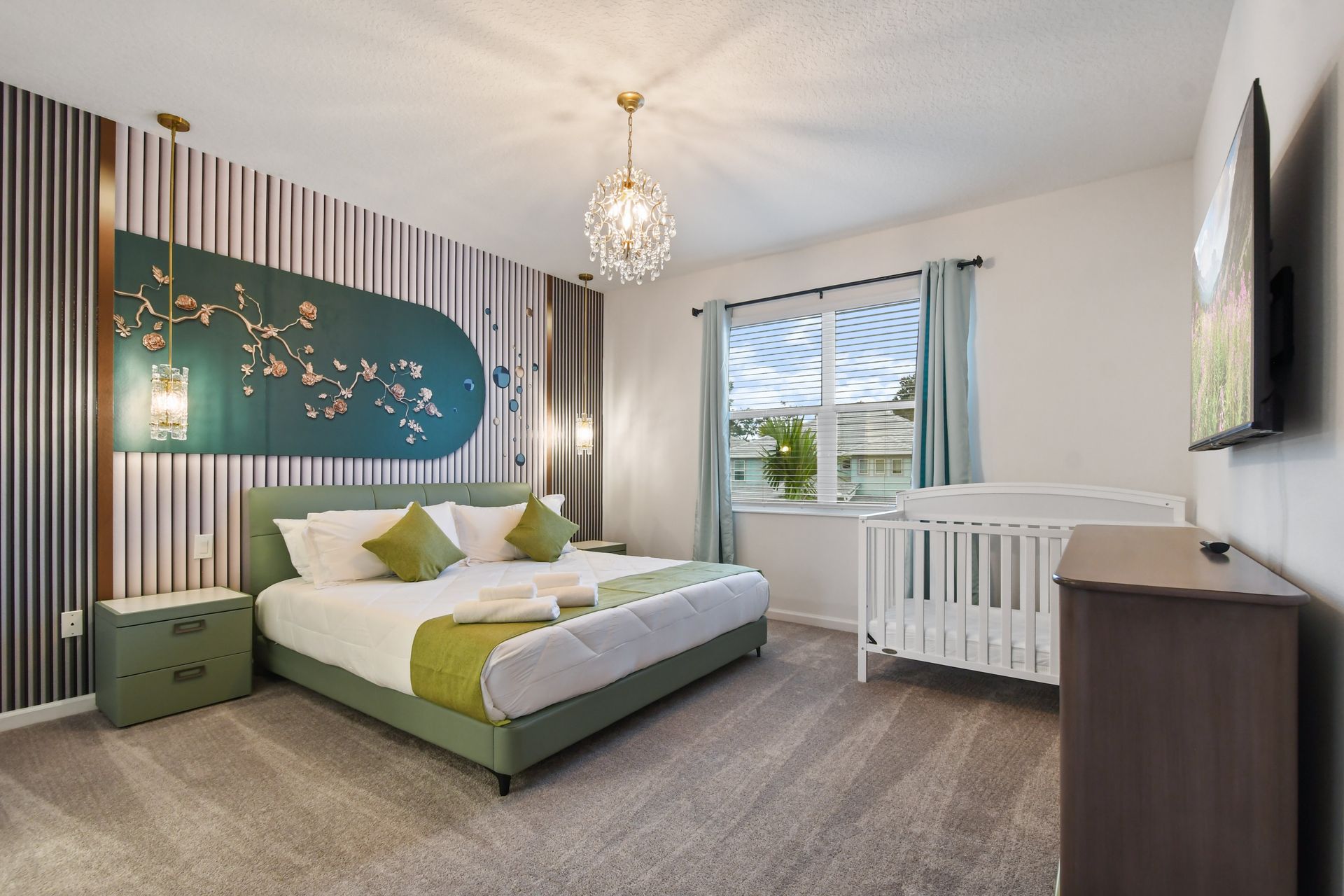 Elegant master bedroom with nature-inspired decor, a chandelier, and a cozy crib.