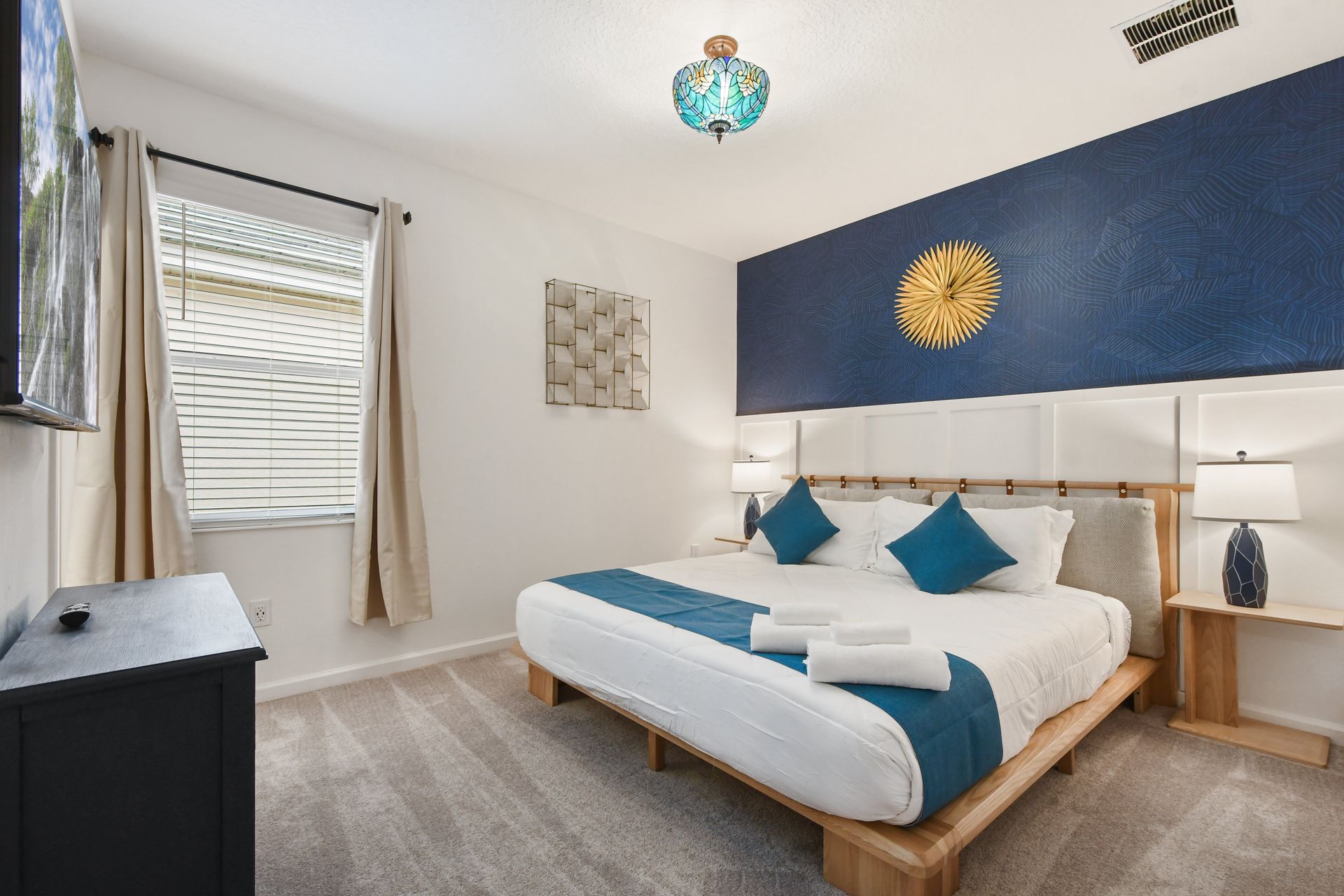Elegant bedroom with a modern wood-accented bed, bold blue decor, and warm lighting.