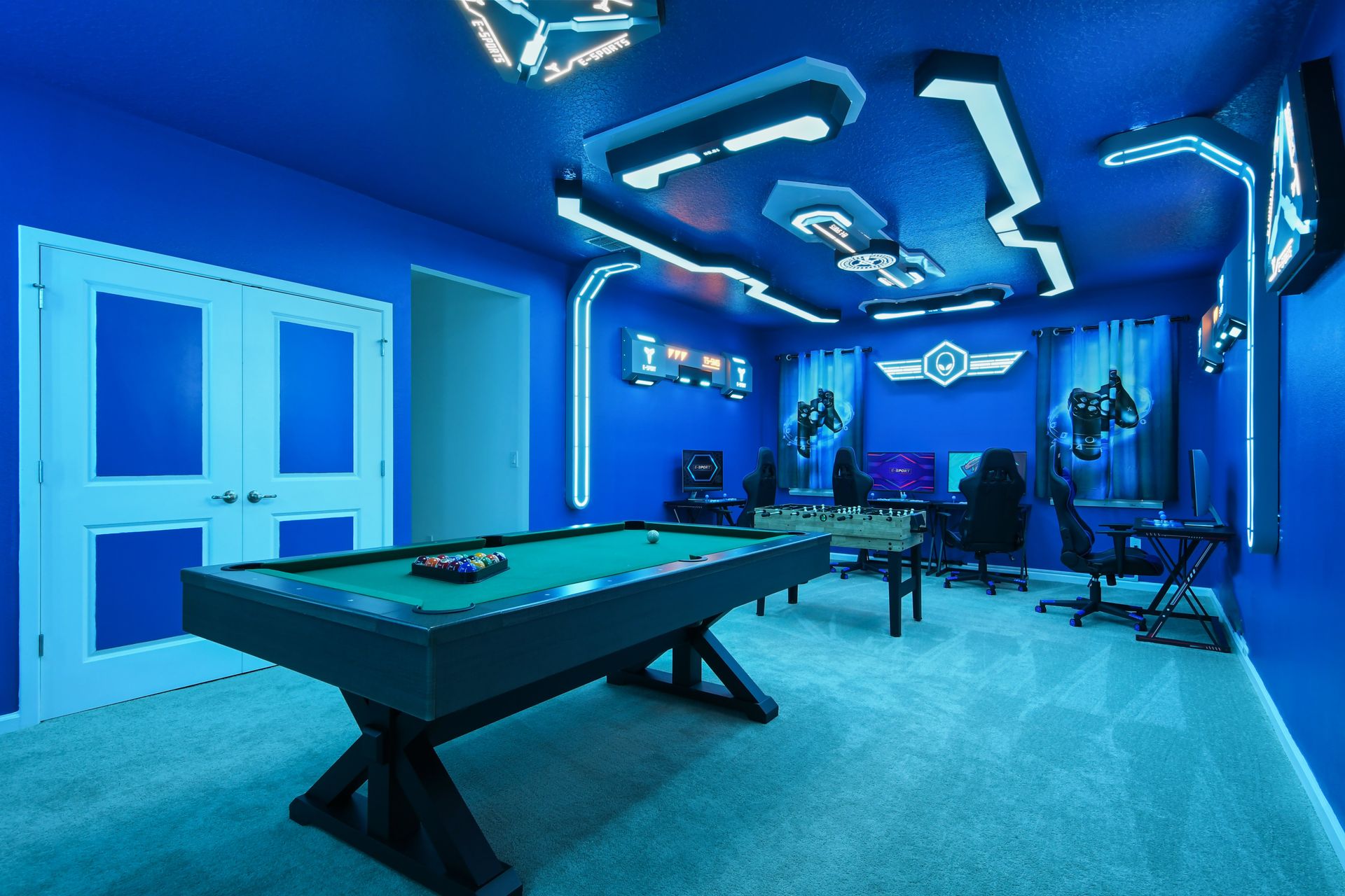 Futuristic game room with neon lighting, gaming stations, pool table, and foosball.