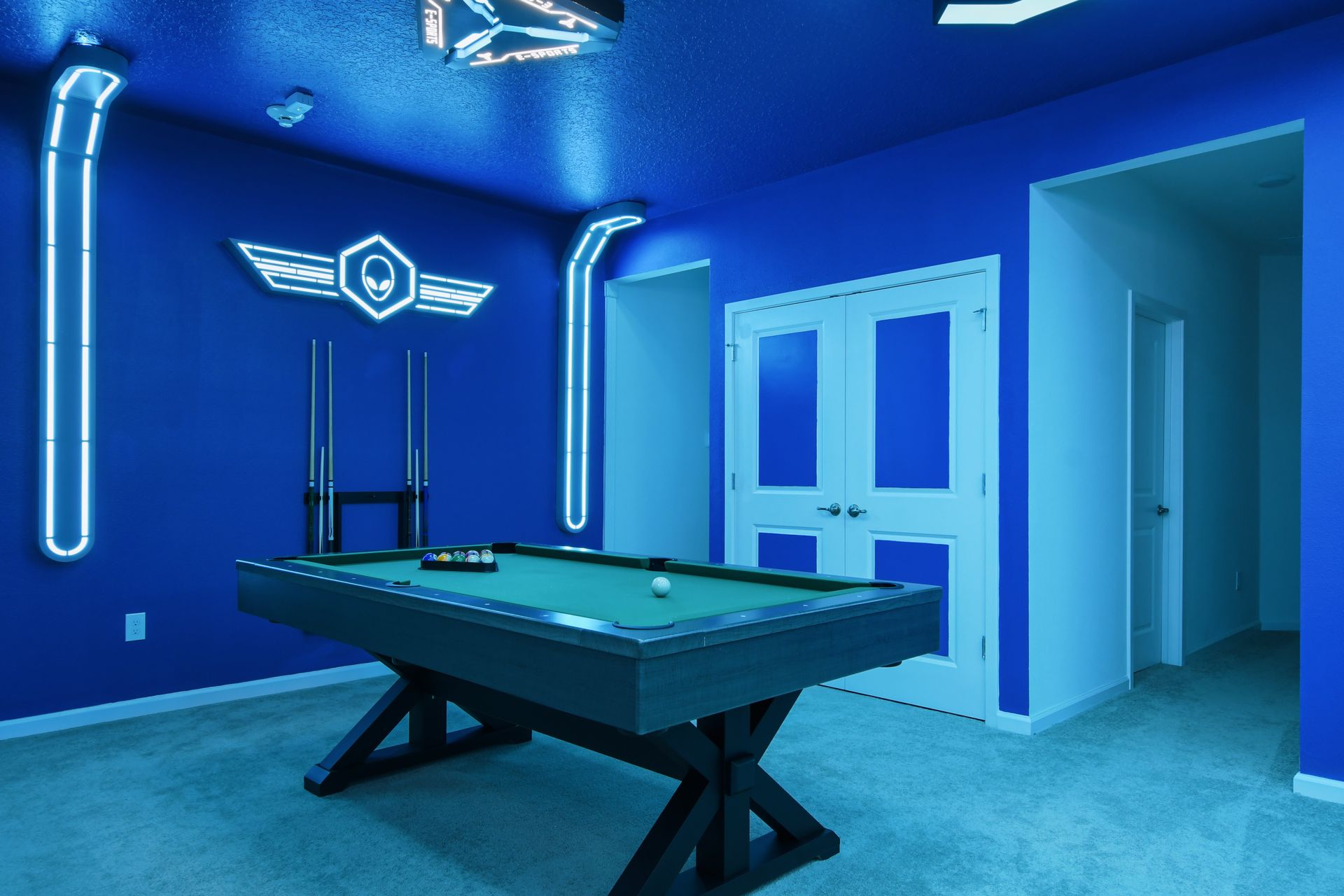Futuristic game room with neon lighting, gaming stations, pool table, and foosball.