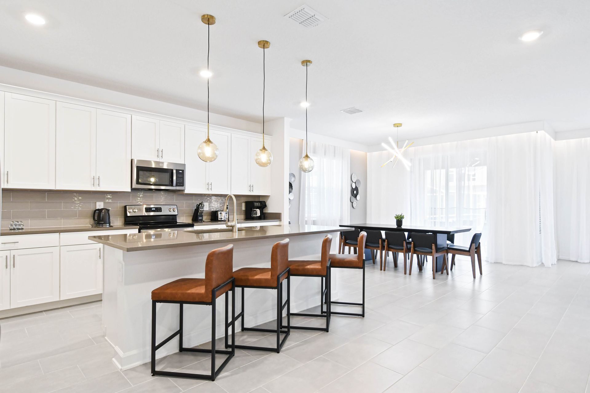Bright open kitchen and dining space with island seating, modern lighting, and style.