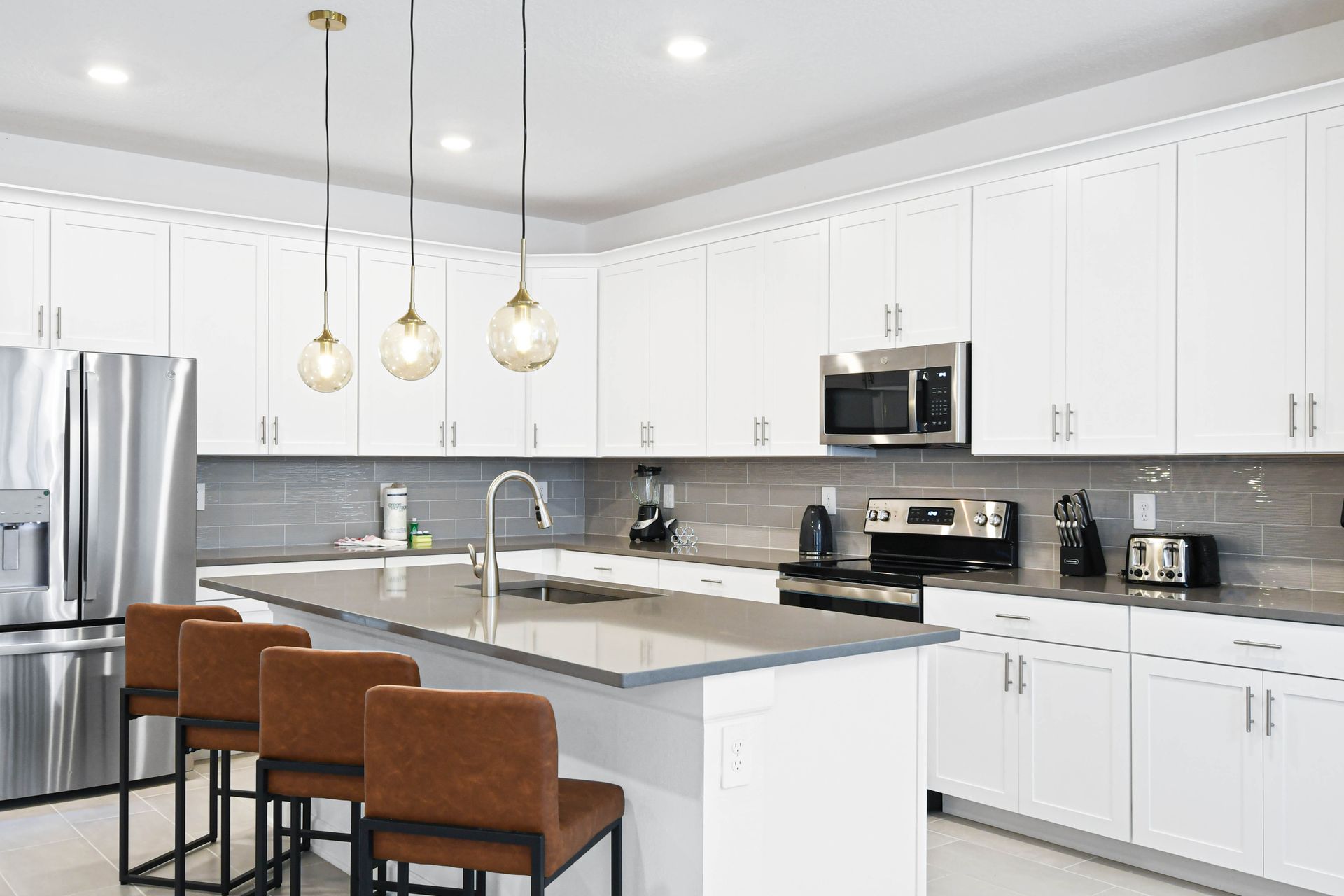 Sleek modern kitchen with stainless steel appliances, large island, and pendant lights.