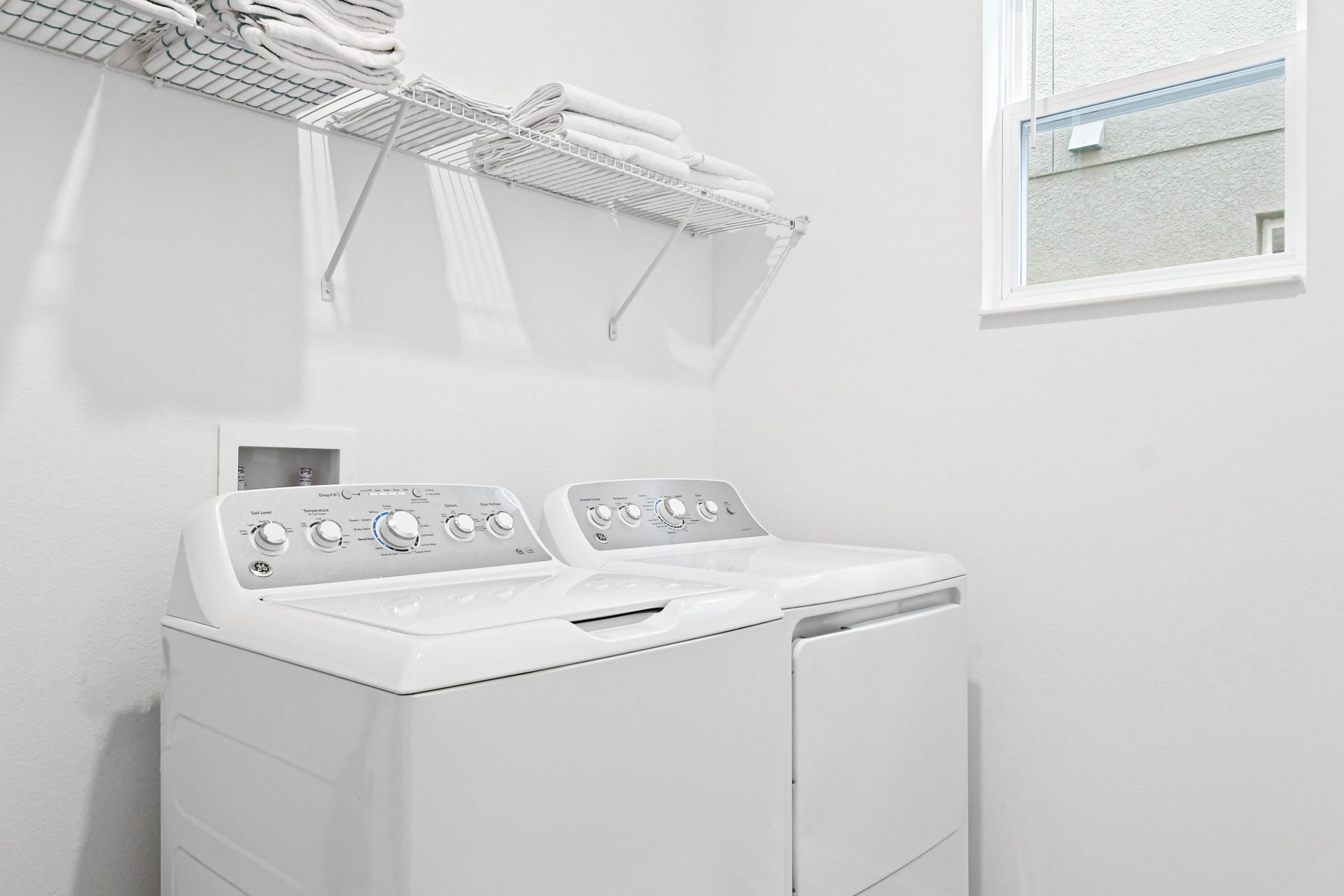 Bright laundry room with washer, dryer, fresh towels, and plenty of natural light.
