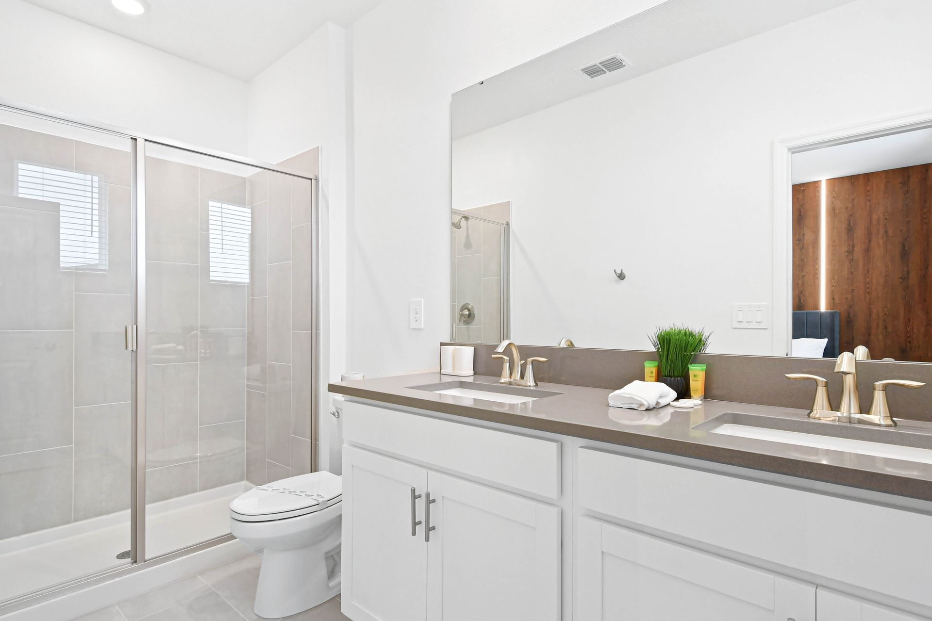 Spacious modern bathroom with double sinks, large glass shower, and elegant touches.