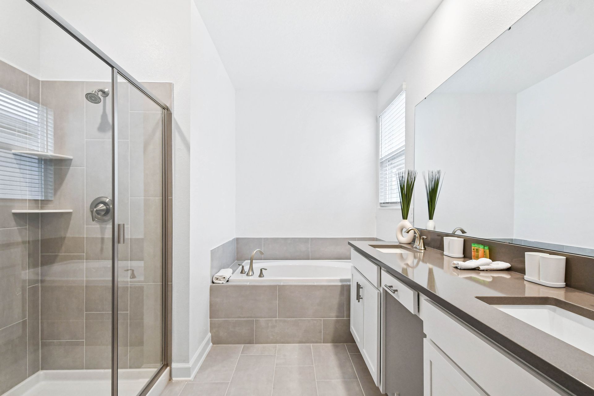 Spacious modern bathroom with double sinks, glass shower, soaking tub, and sleek design.