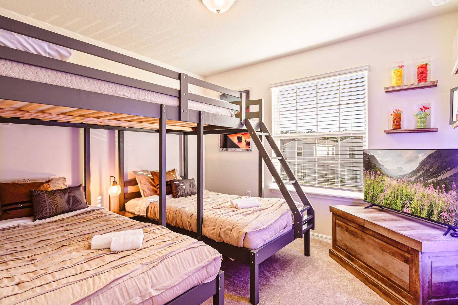 A bunk bed setup with one full bed on top and two twin beds below.
