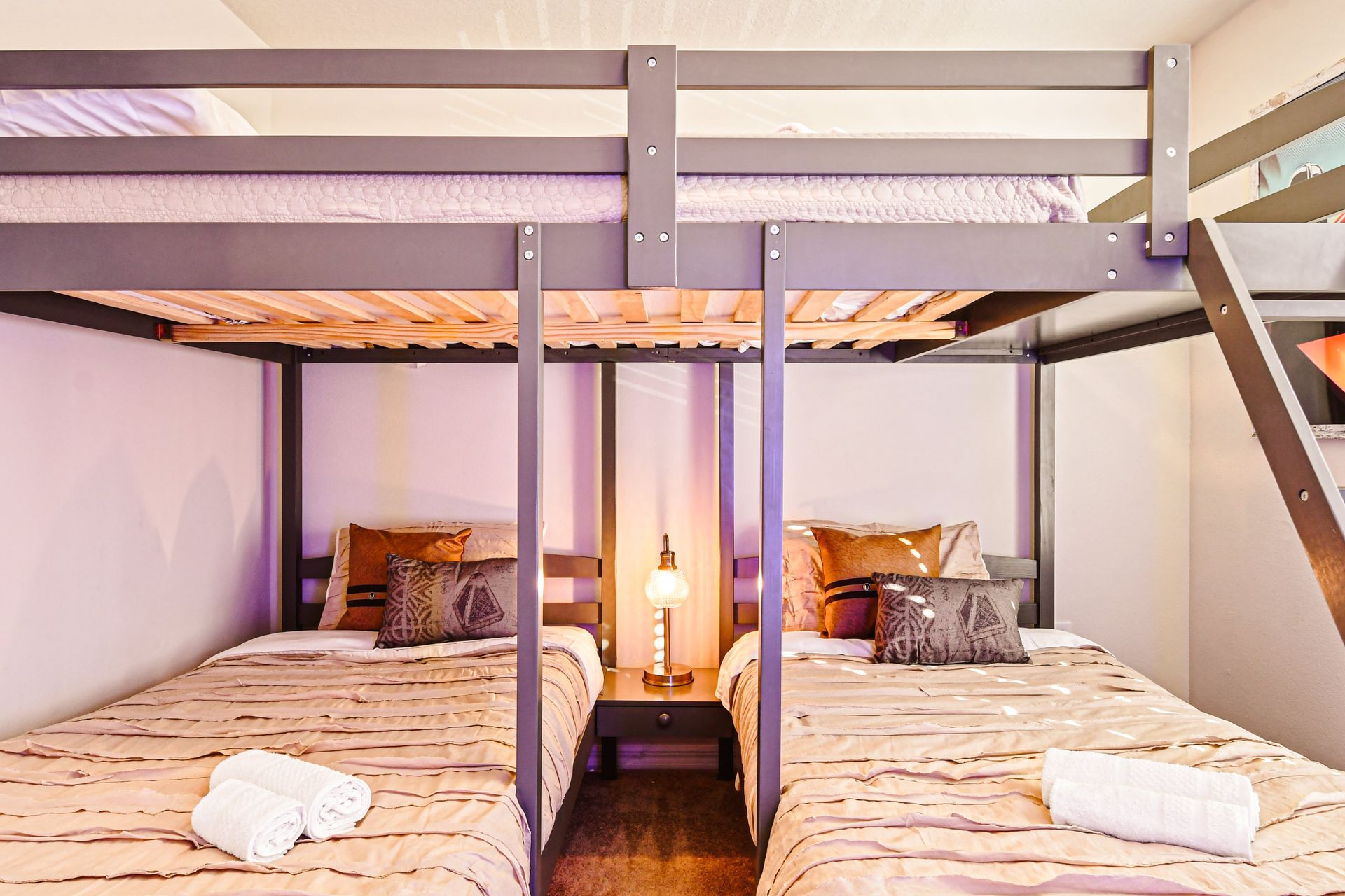 A bunk bed setup with one full bed on top and two twin beds below.