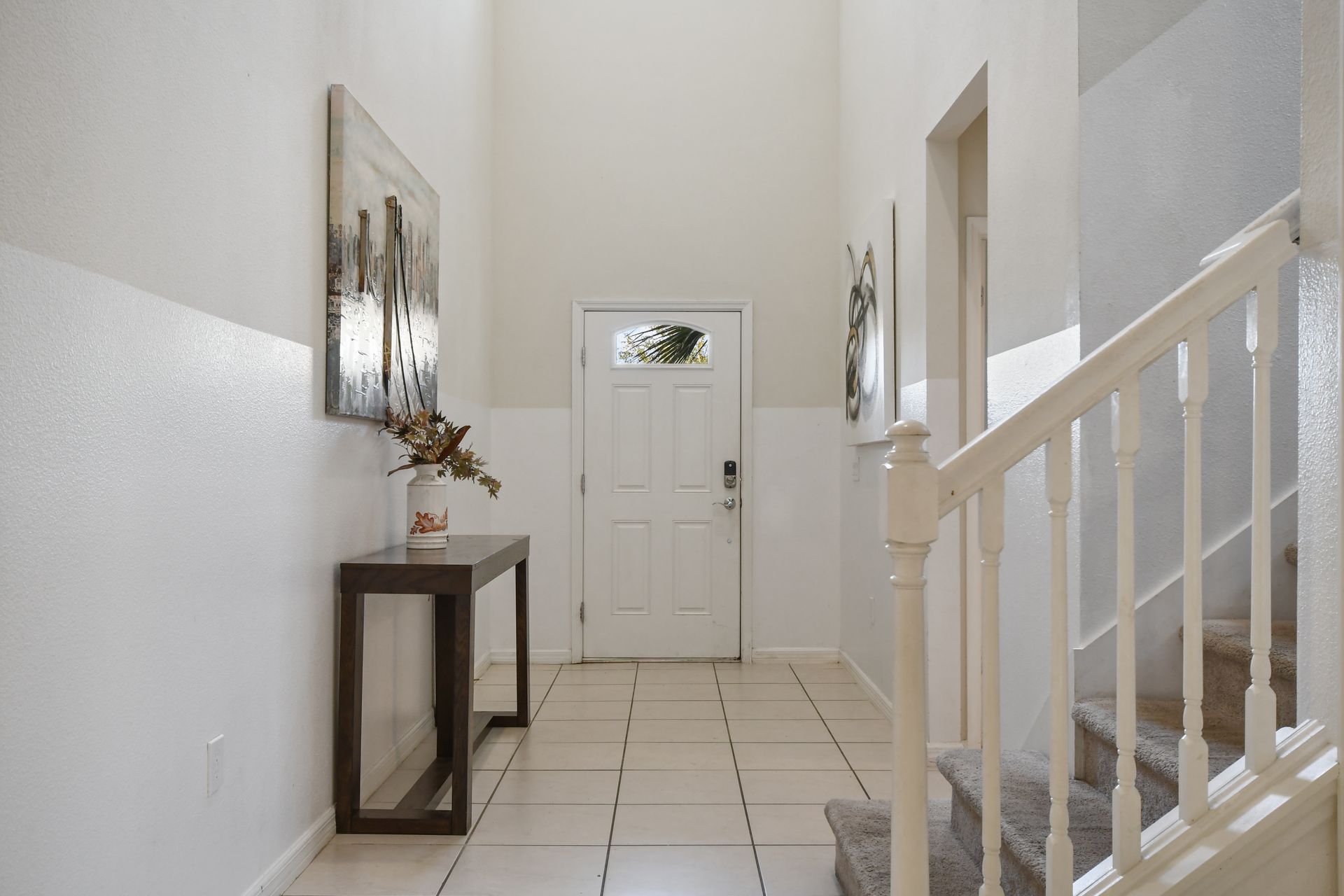 Bright entryway with high ceilings, modern decor, and a welcoming, airy feel.