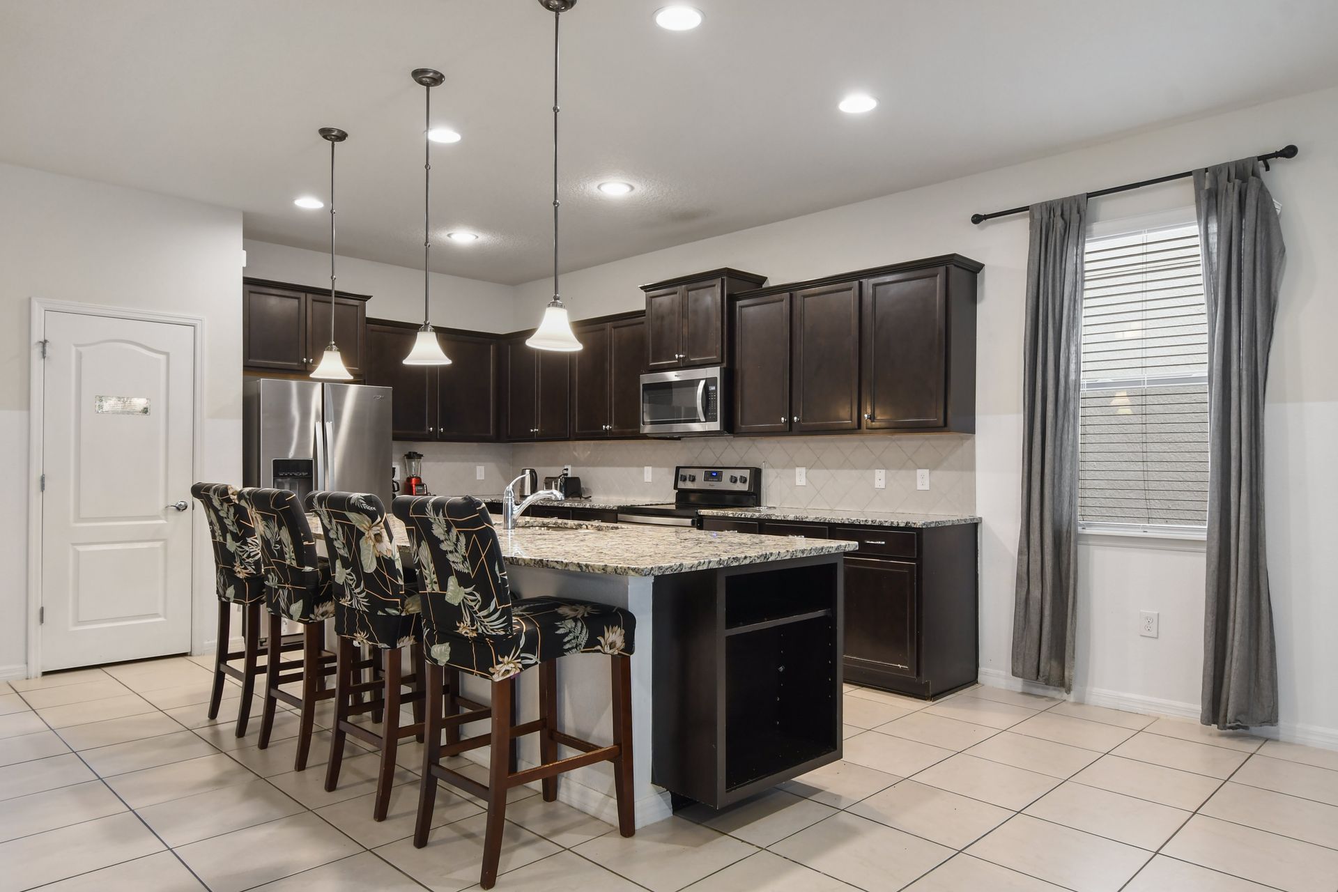 Fully equipped modern kitchen with granite counters, bar seating, and stainless steel.