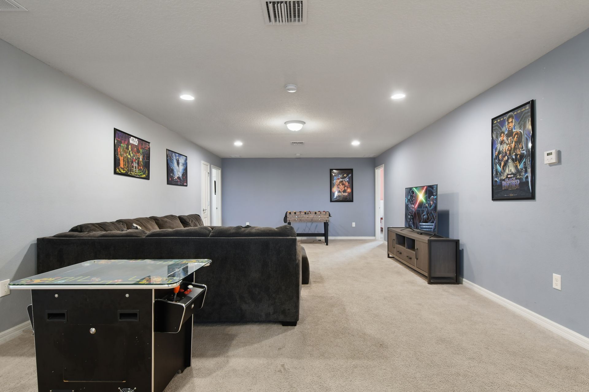 Entertainment loft with arcade game, foosball, plush seating, and large screen TV.