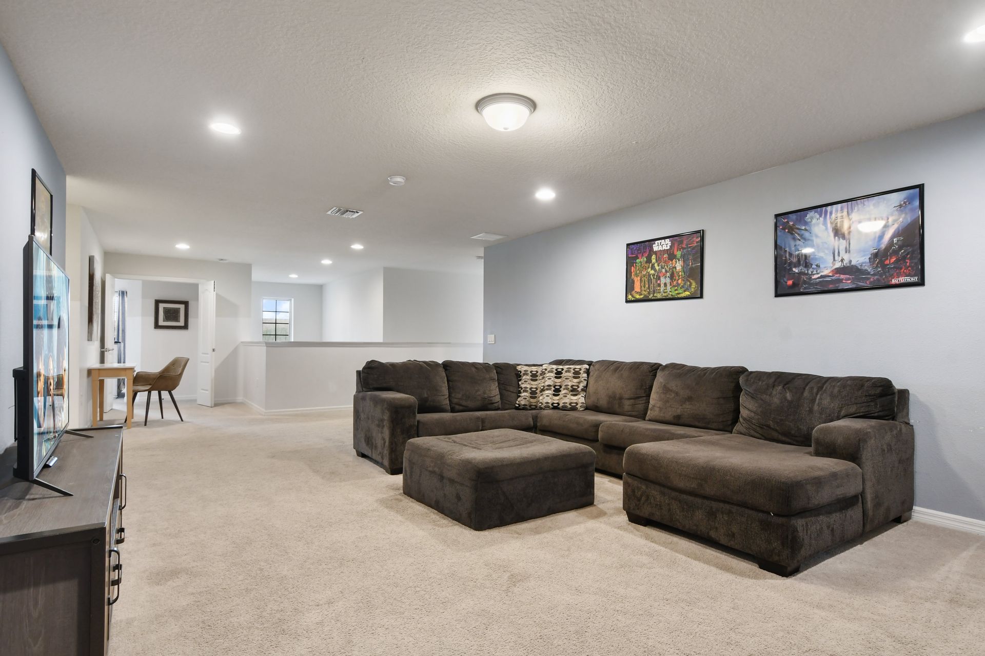 Relaxing upstairs lounge with cozy sectional, large TV, and a fun gaming vibe.