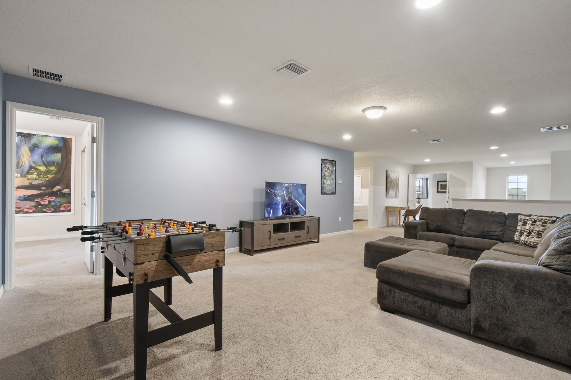 Spacious game room with foosball, large sectional, and entertainment-ready TV setup.
