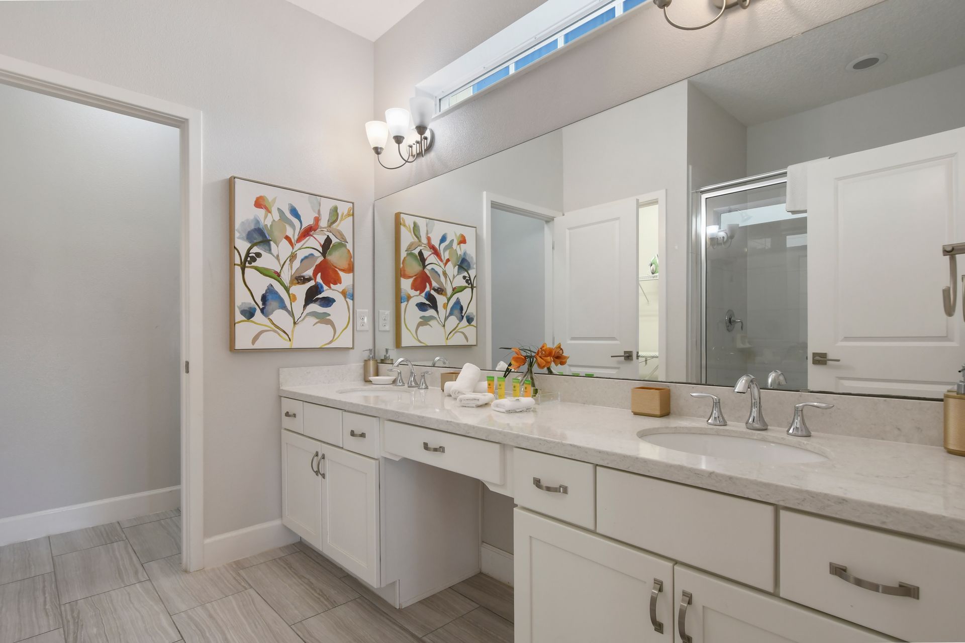 Bright bathroom with dual sinks, large mirror, and elegant decor