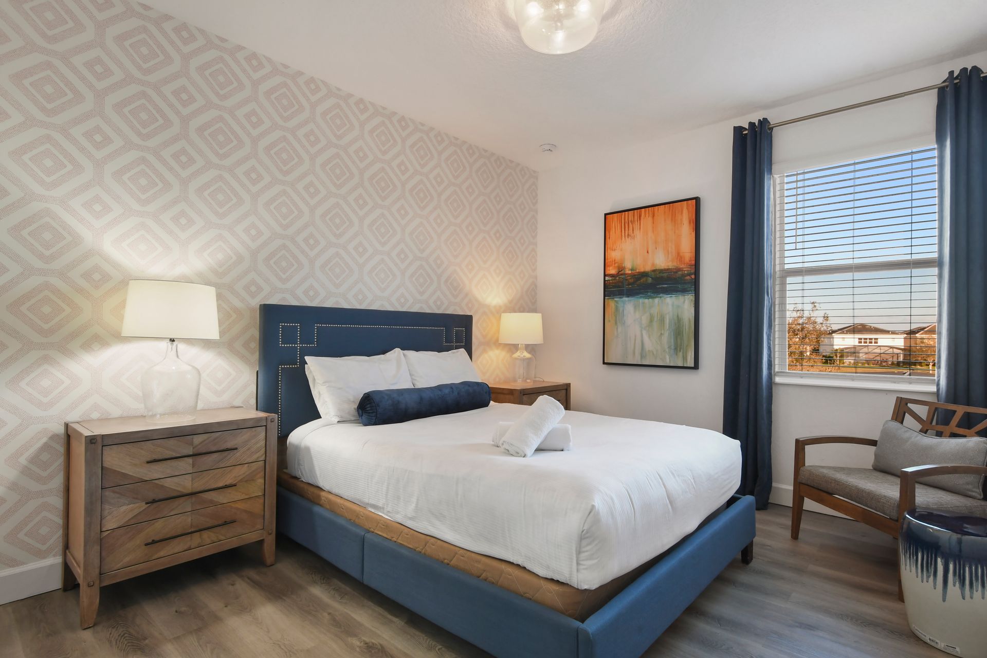 Charming bedroom with stylish wallpaper, comfy bed, and cozy seating