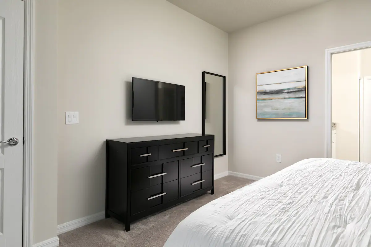 Modern bedroom with sleek decor, smart TV, and calming neutral tones.