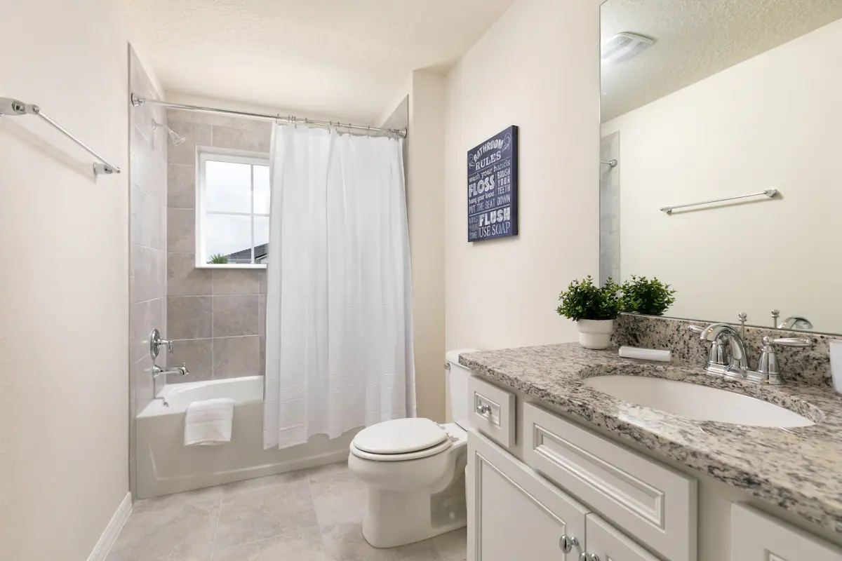 Bright bathroom with granite vanity, tiled shower-tub combo, and modern chrome fixtures.