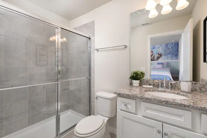 Stylish bathroom with granite countertop, glass walk-in shower, and modern lighting.