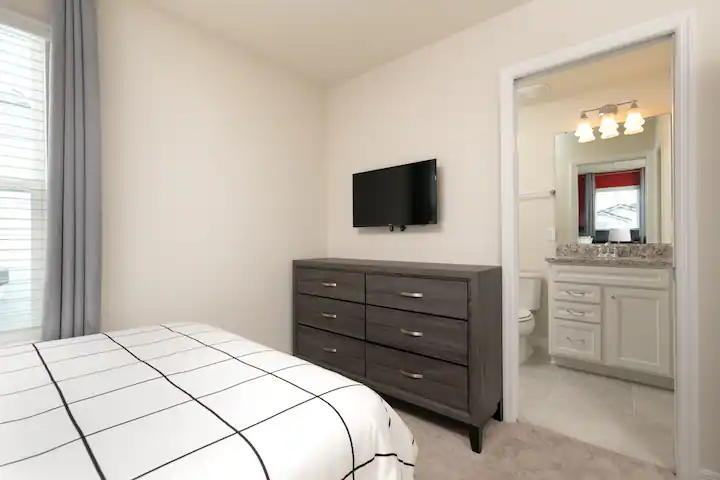 Cozy bedroom with ensuite bath, smart TV, and modern minimalist decor.
